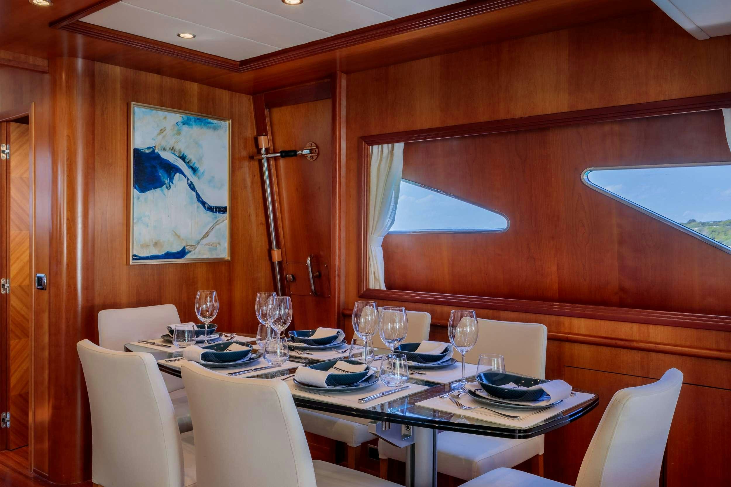 a dining table with plates and glasses aboard FREEDOM Yacht for Charter