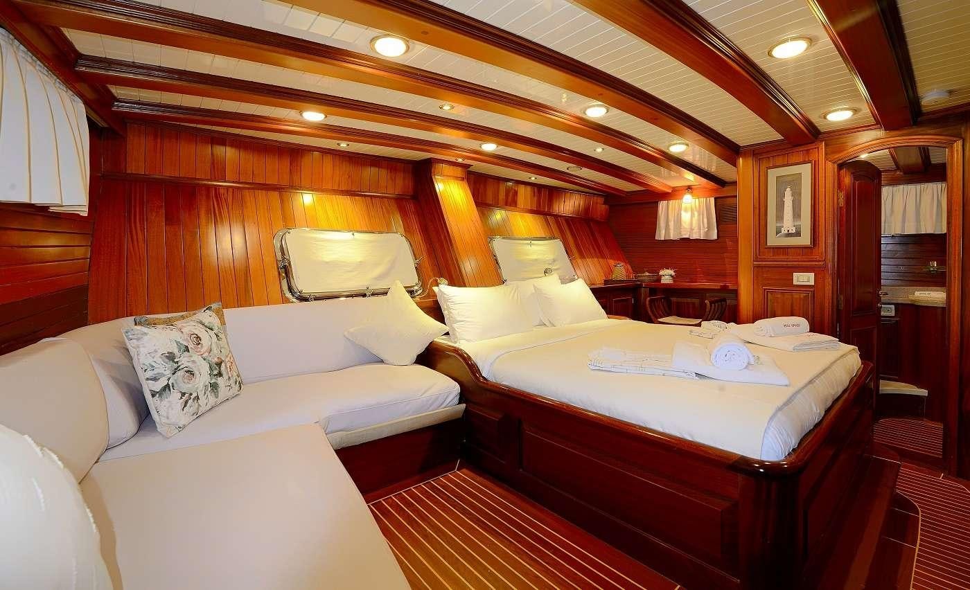 a room with a bed and a chair aboard ECCE NAVIGO Yacht for Charter