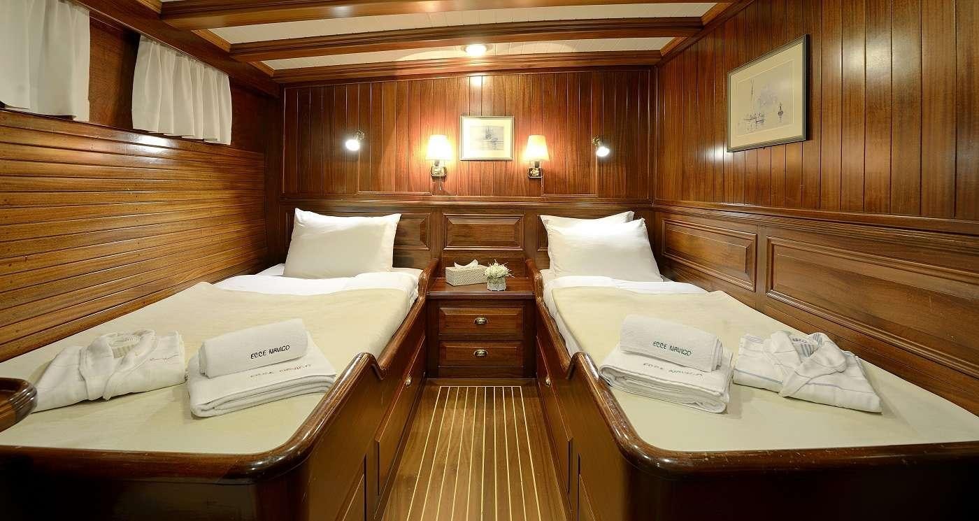 a room with beds and a desk aboard ECCE NAVIGO Yacht for Charter
