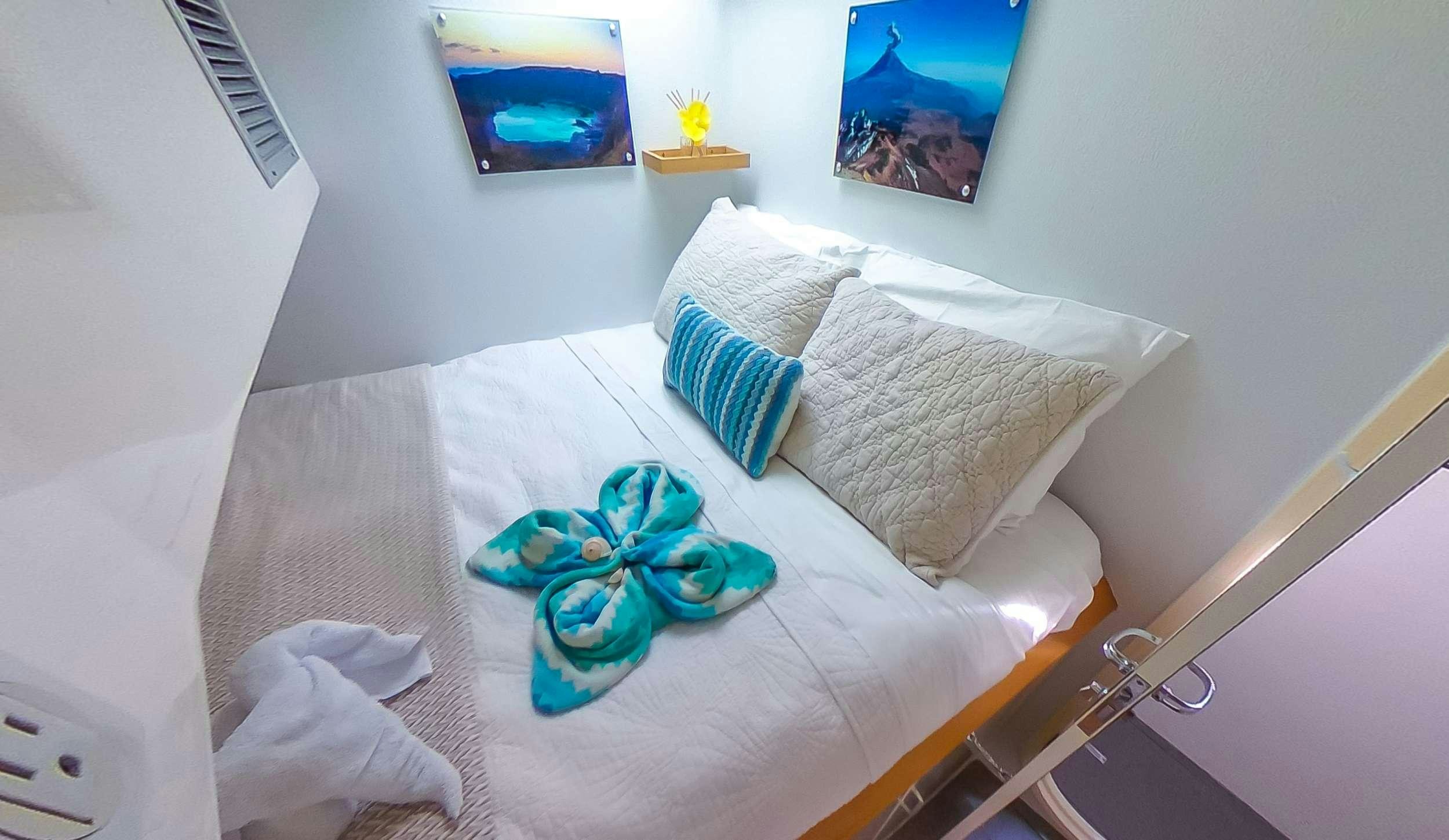 a bed with a white sheet and blue pillows aboard YES DEAR Yacht for Charter