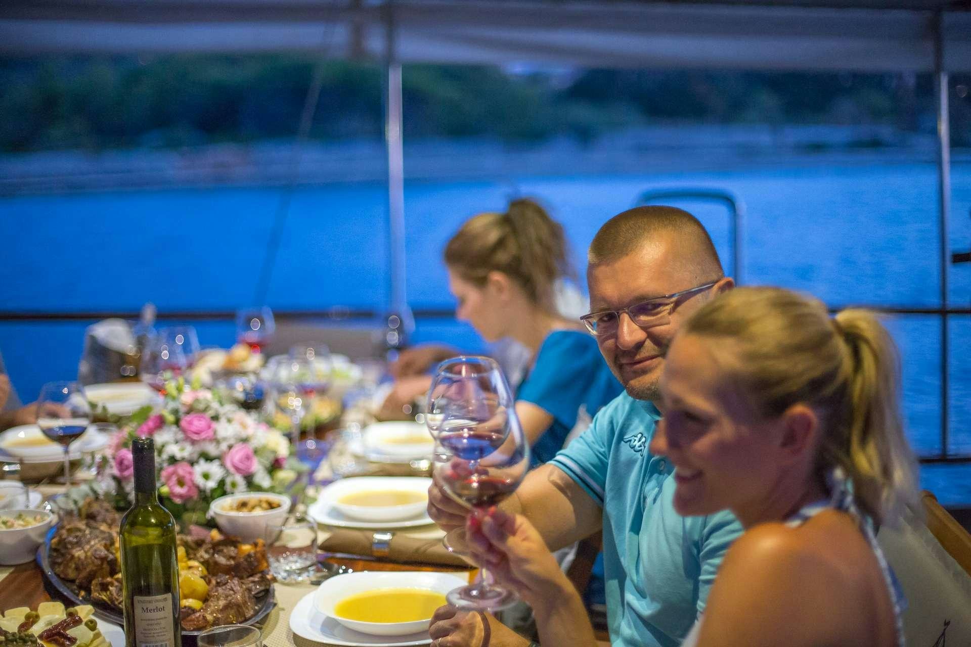 a group of people sitting at a table with food and drinks aboard ALLUREE Yacht for Charter