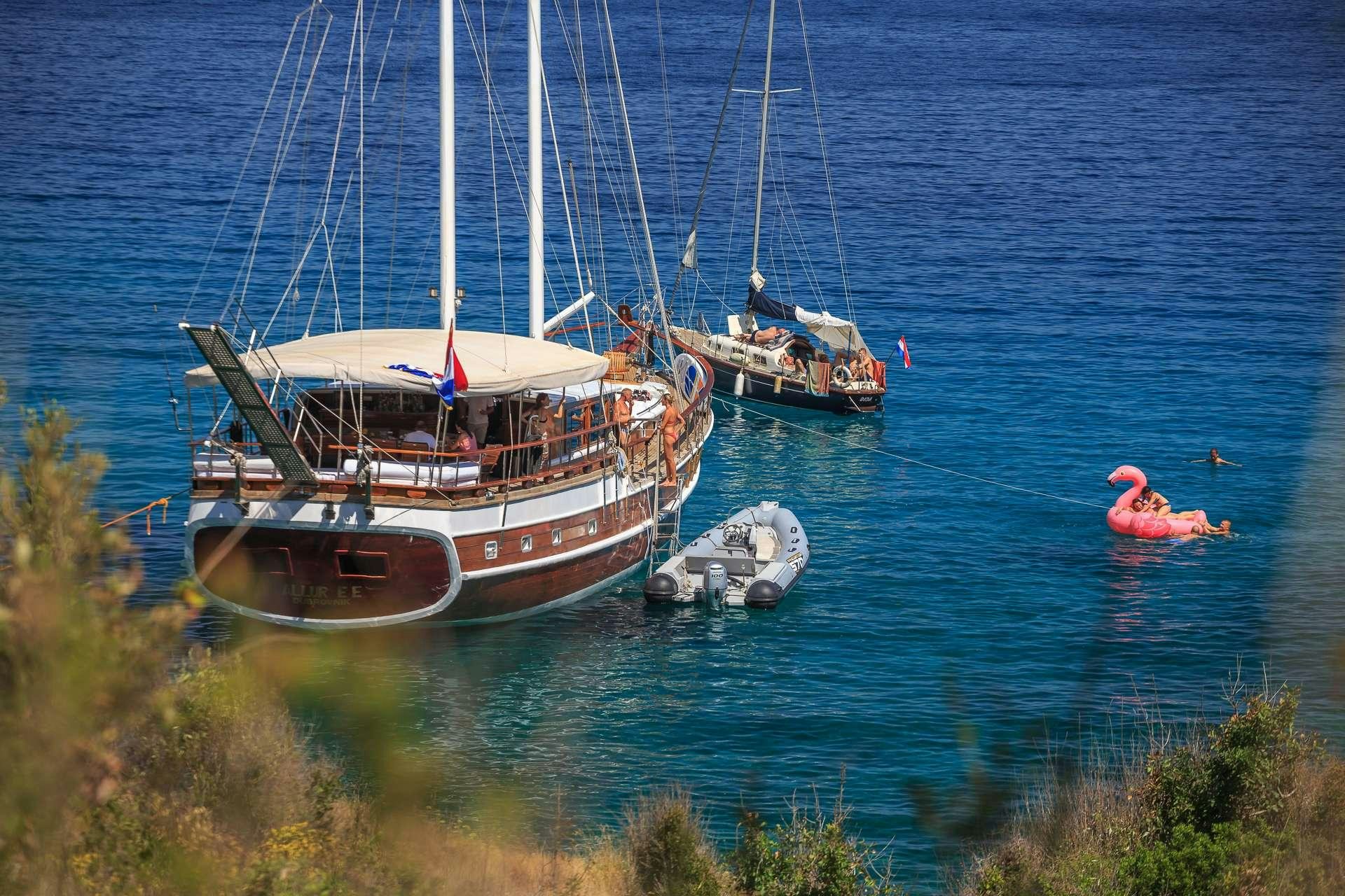 a person swimming in the water next to a boat aboard ALLUREE Yacht for Charter