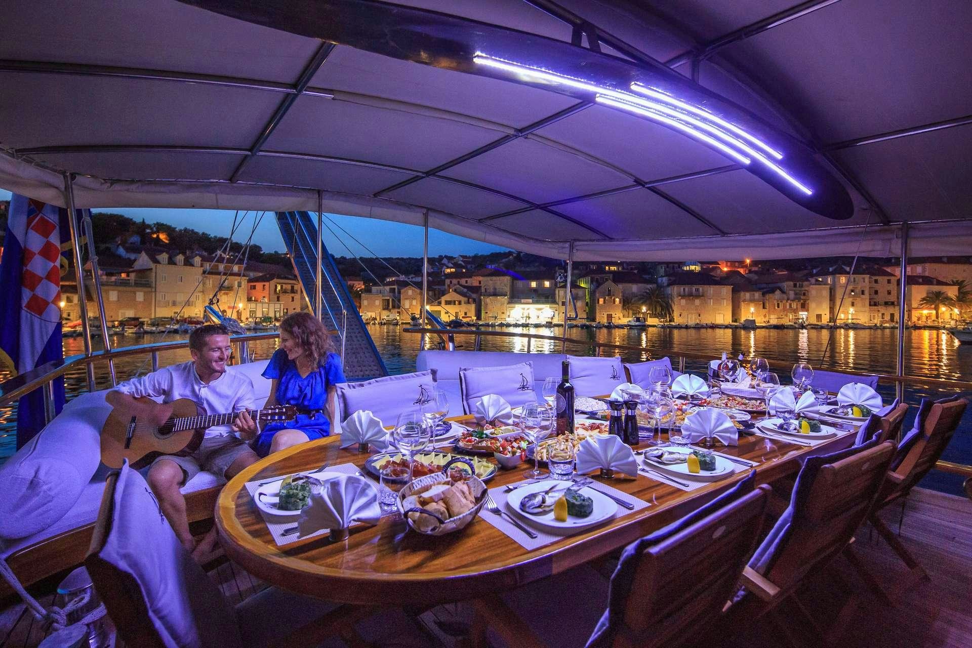 a group of people sitting at a table with food and drinks aboard ALLUREE Yacht for Charter