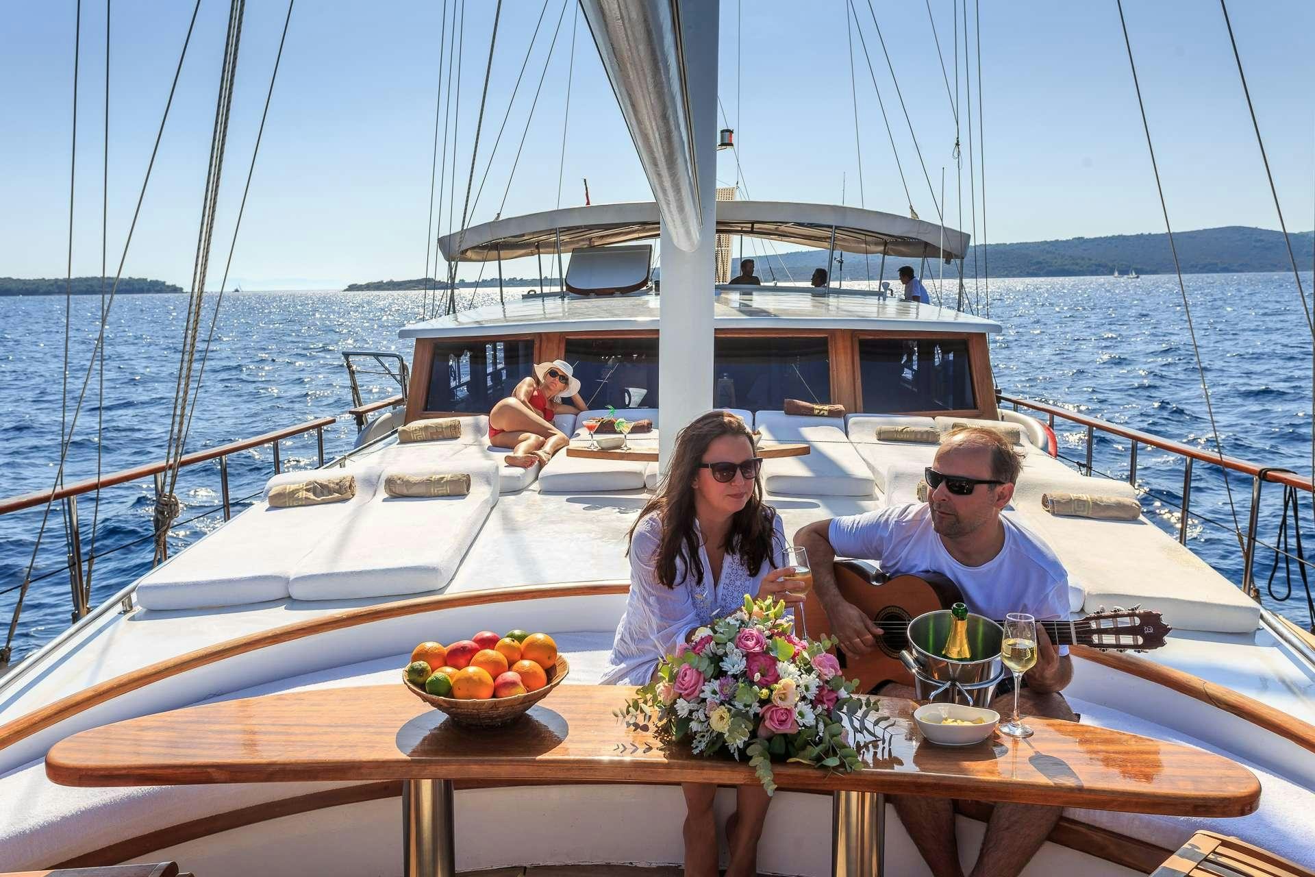 a man and woman sitting on a boat with a woman sitting in the water and a man sitting aboard ALLUREE Yacht for Charter
