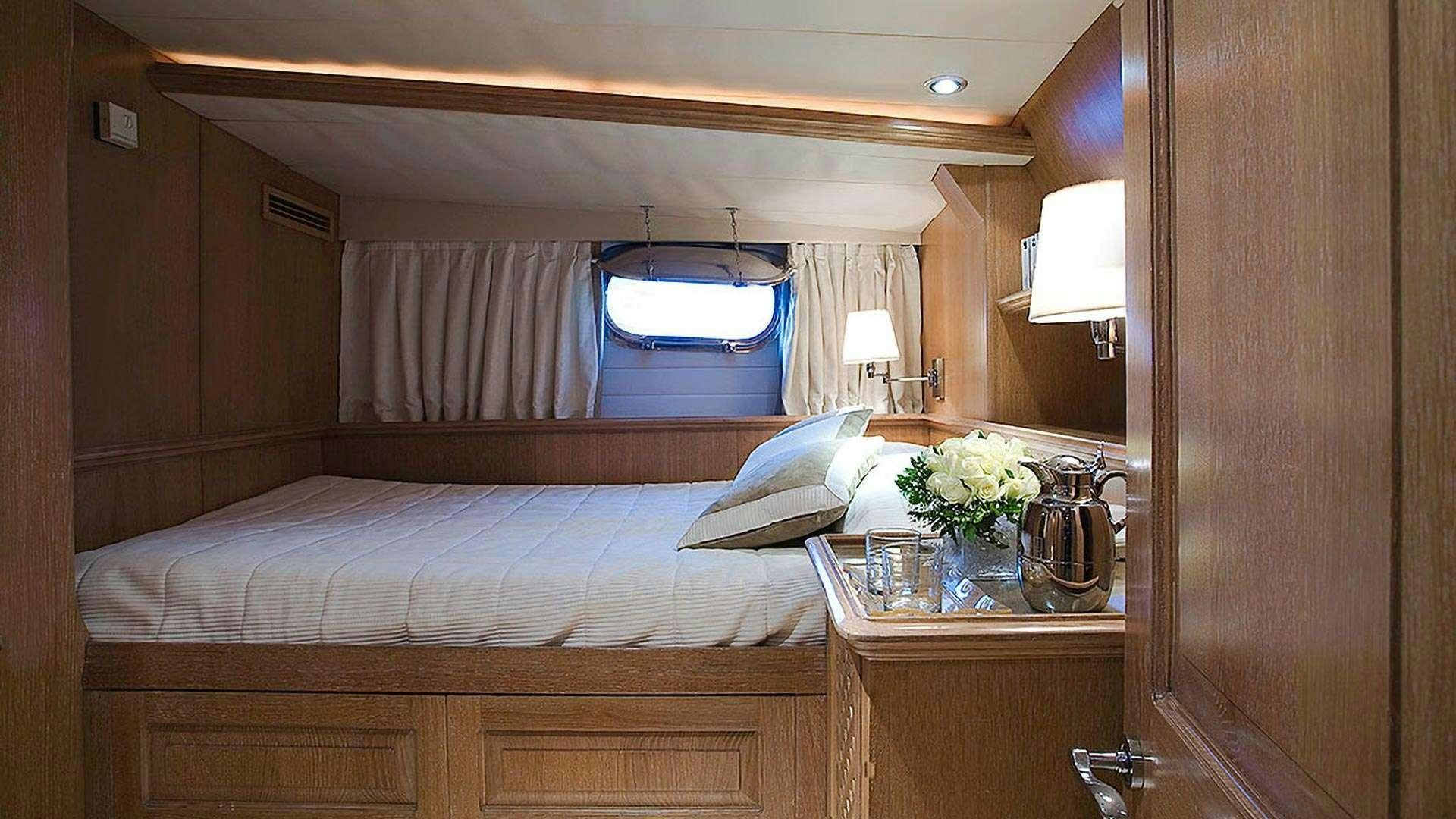 a bed with a table and a mirror aboard ALTHEA Yacht for Charter