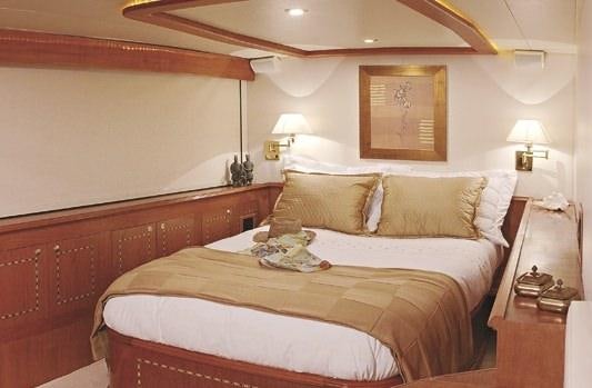 a bed with a white comforter aboard ATLANTIS II Yacht for Charter