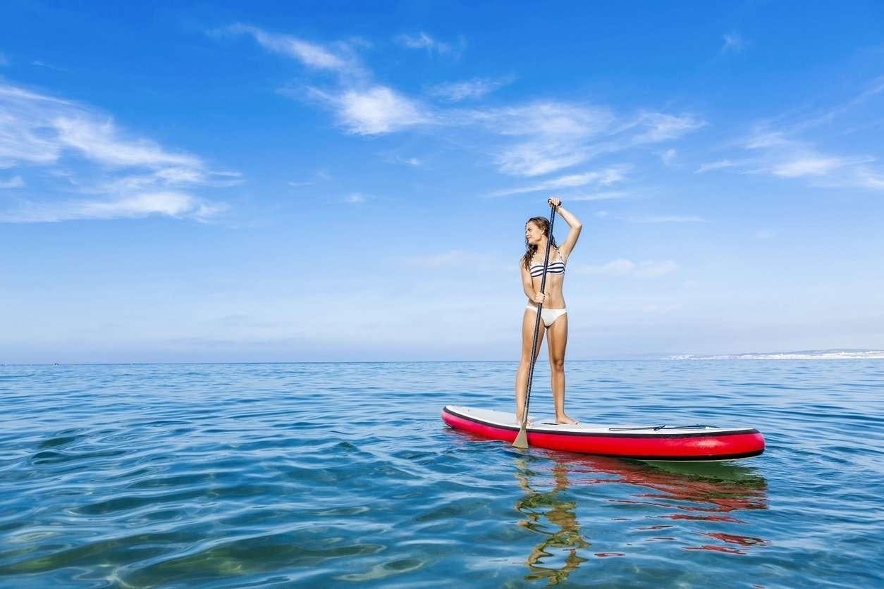 a person standing on a red surfboard in the ocean aboard EDDIES IN TIME Yacht for Charter