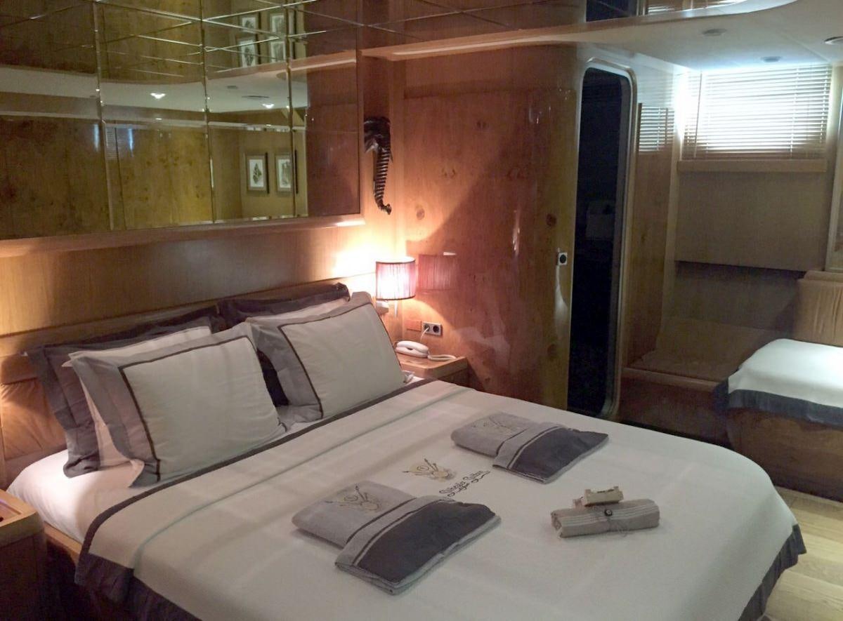 a bed with a white sheet and a book on it aboard SUHEYLA Yacht for Charter