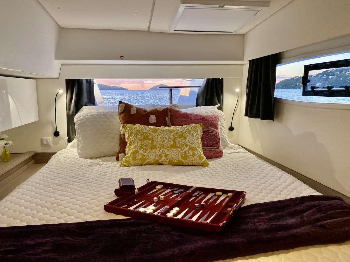 a bed with a red and white blanket and pillows aboard HERO'S JOURNEY Yacht for Charter