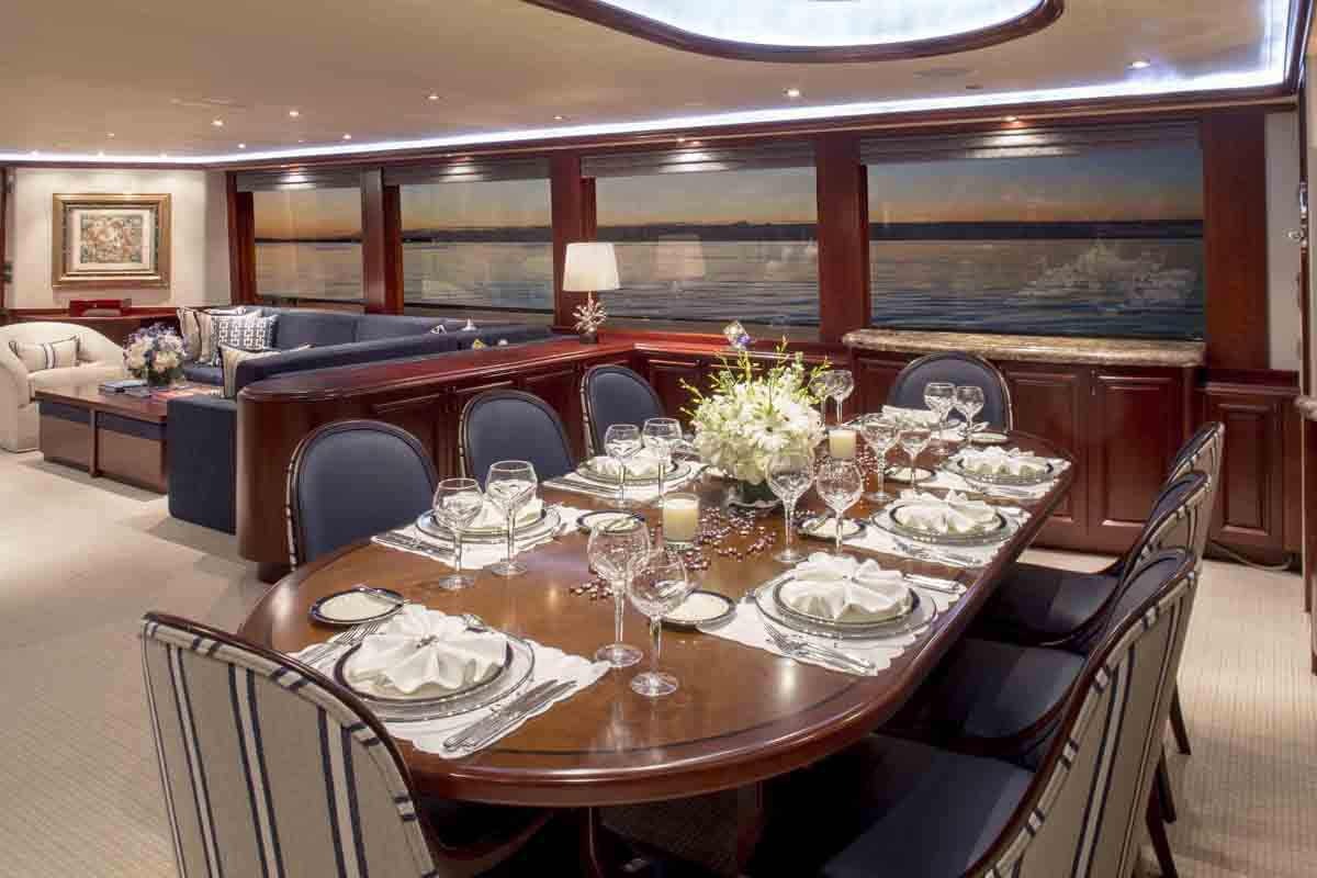 a large dining table with a set of chairs and a large chandelier aboard PLAN A Yacht for Charter