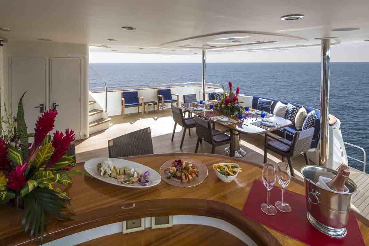 a dining table with a view of the ocean aboard PLAN A Yacht for Charter