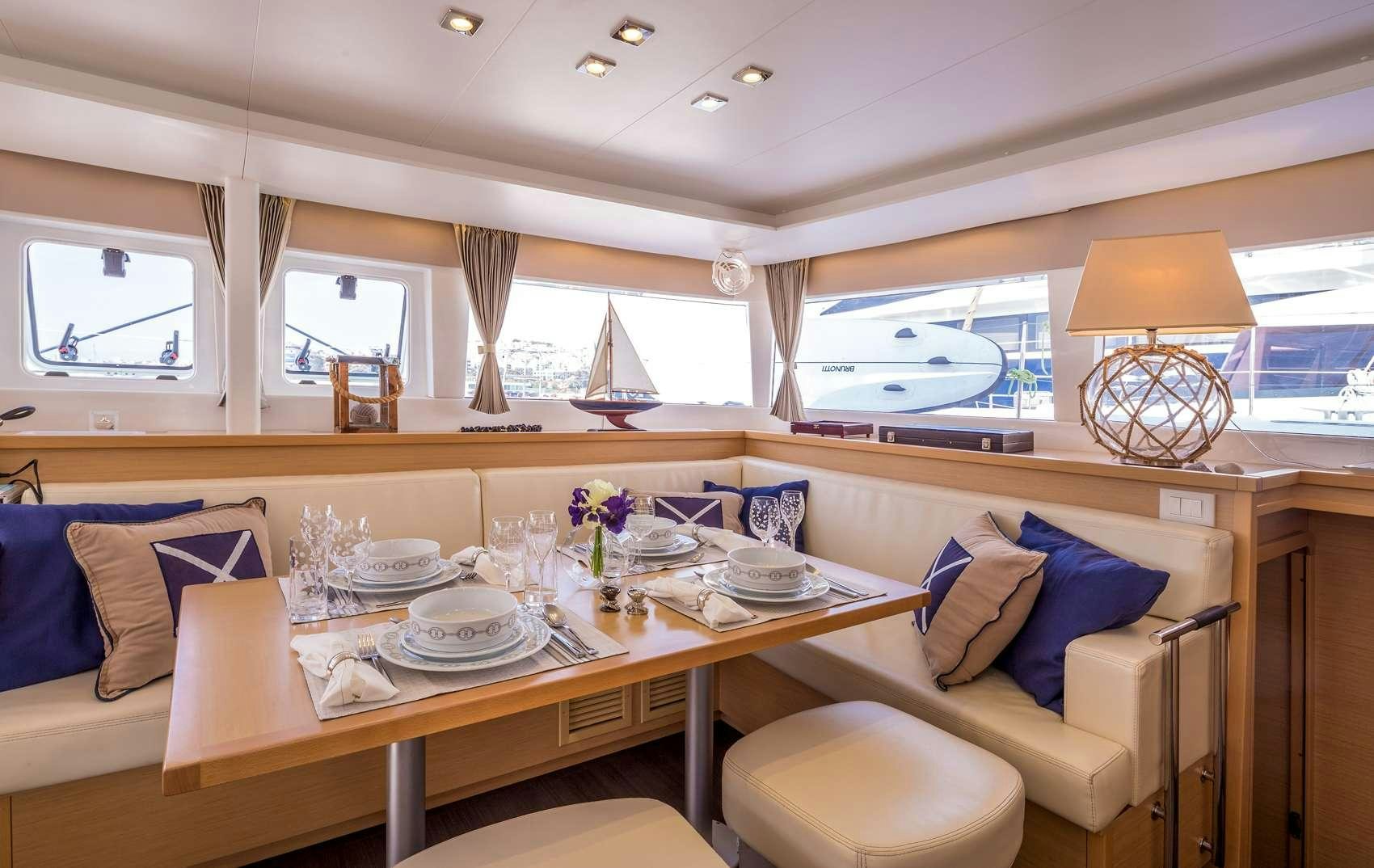 a large dining table with a large window aboard NEW HORIZONS Yacht for Charter