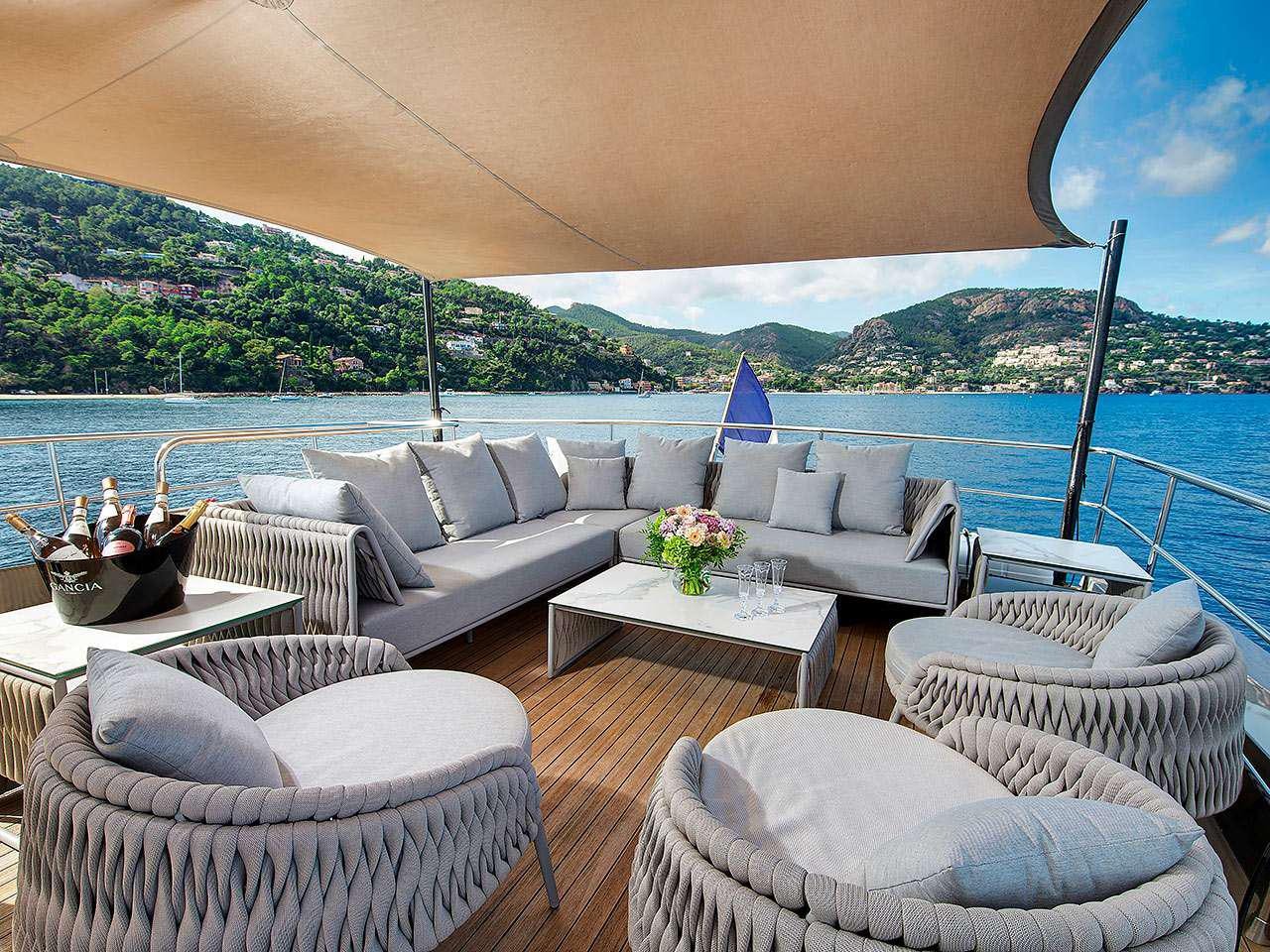 a living room with a large body of water and mountains in the background aboard KOKONUT'S WALLY Yacht for Charter