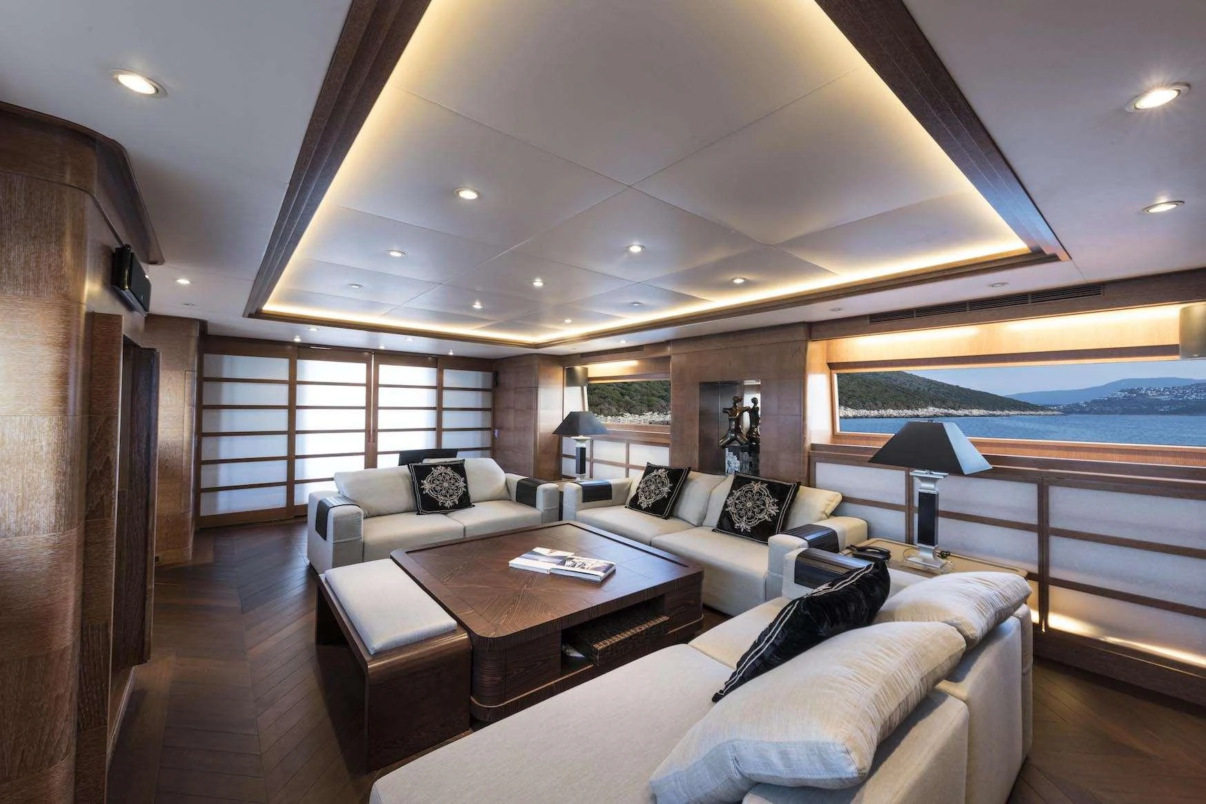 The salon features luxurious seating with ample natural light and elegant wood finishes. aboard KALIMERA Yacht for Charter