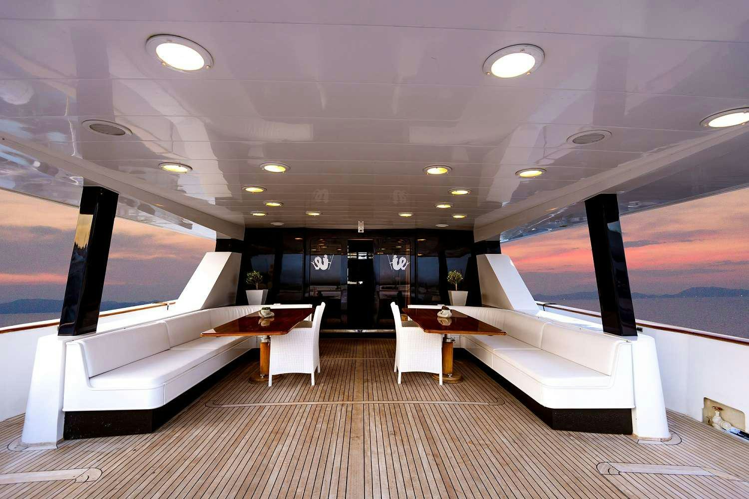 a room with a large white bed and a table with chairs aboard LADY RINA Yacht for Charter