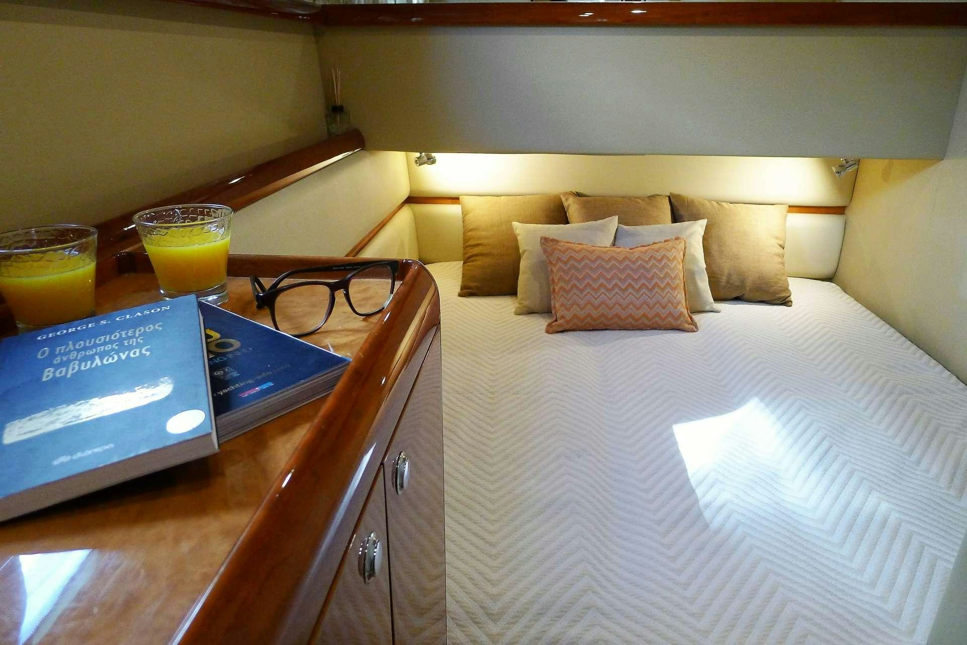 a bed with a glass of juice and a book on it aboard ESPERANCE III Yacht for Charter