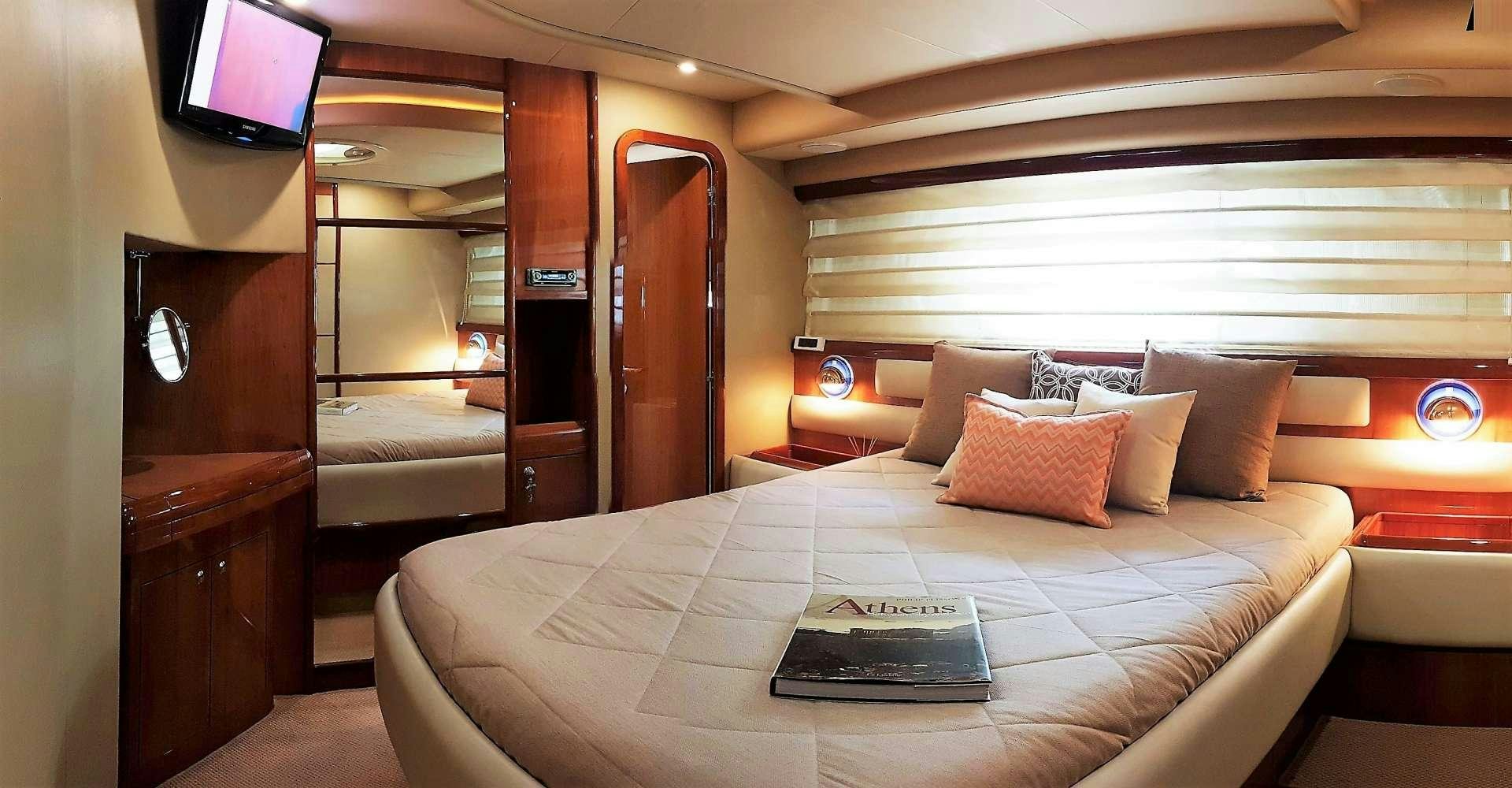 a bed with a white sheet and pillows in a room with a television aboard ESPERANCE III Yacht for Charter