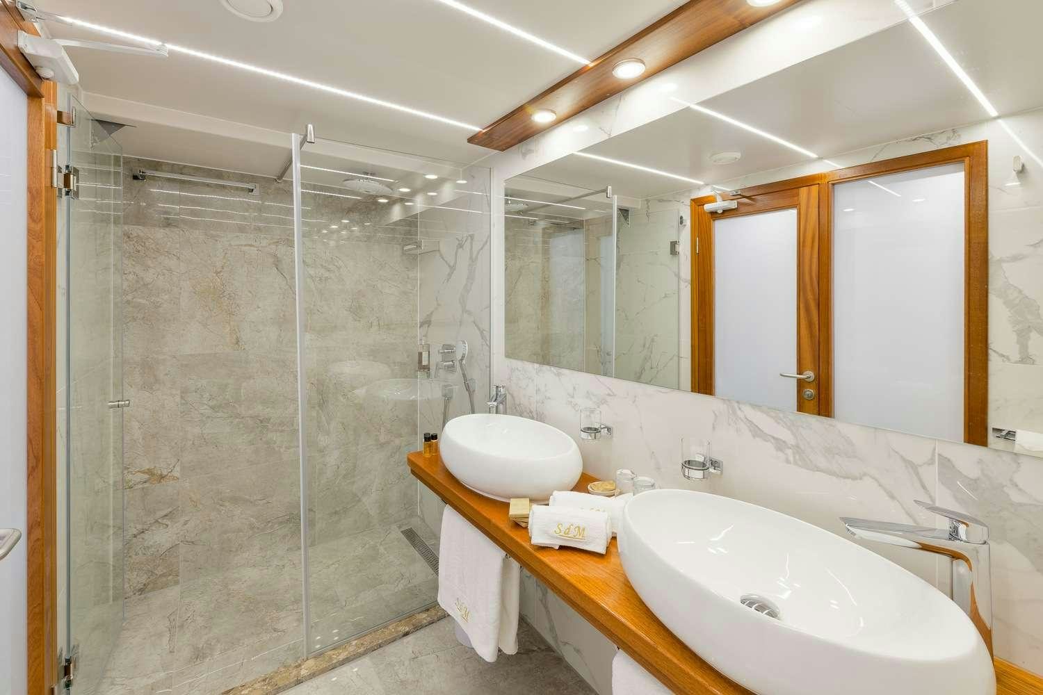 a bathroom with a shower and sinks aboard SON DE MAR Yacht for Charter