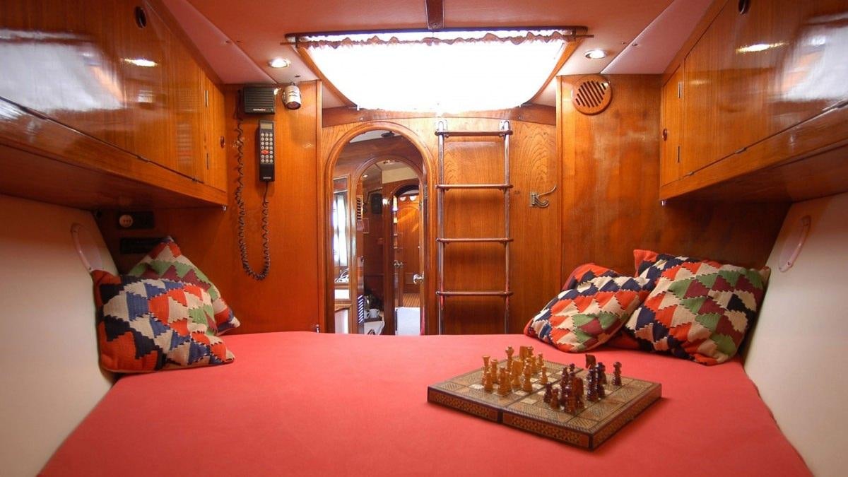 a large bed with a red sheet aboard SHAITAN (65' SWAN) Yacht for Charter
