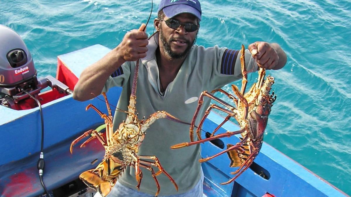 a man holding a fish aboard SHAITAN (65' SWAN) Yacht for Charter