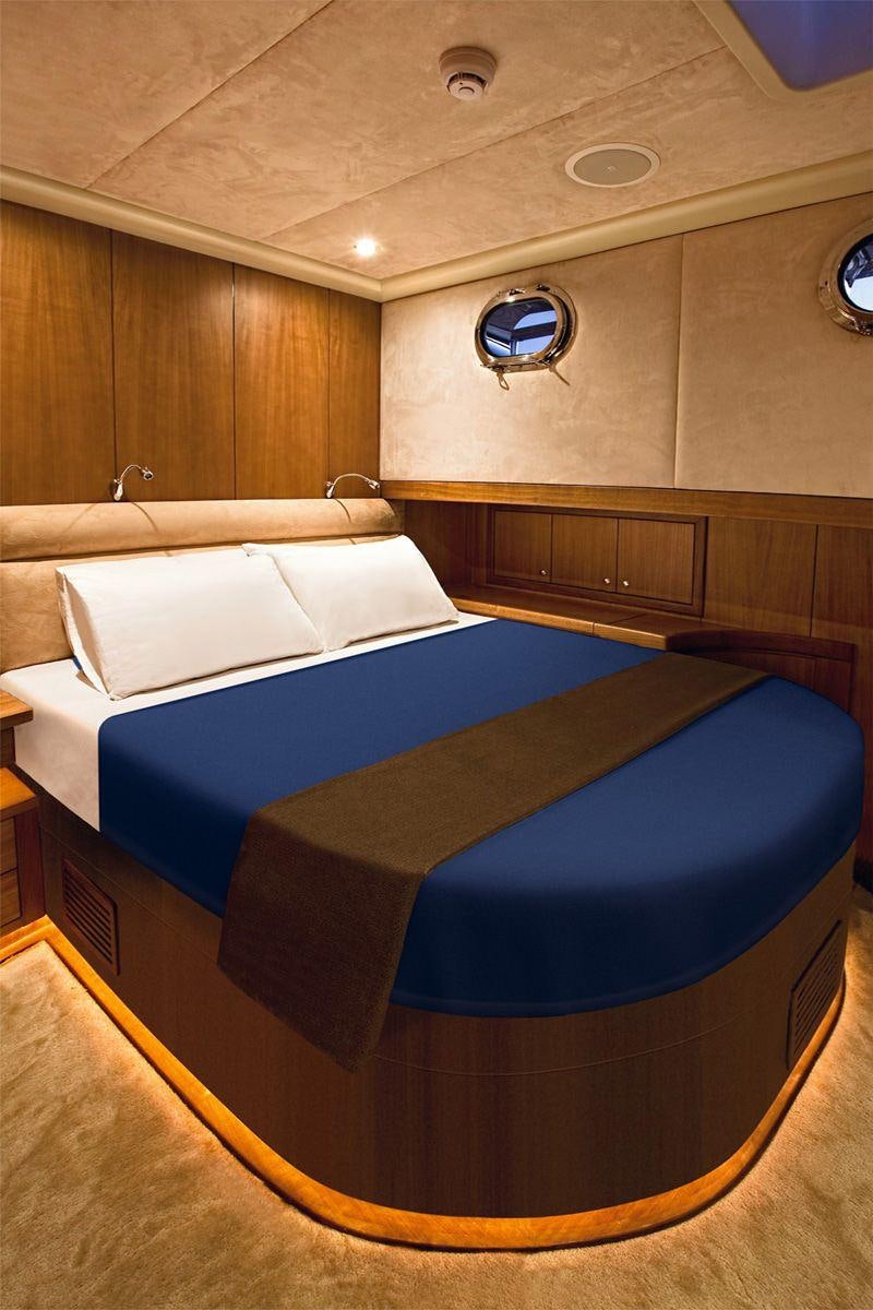 a bed with a blue sheet aboard MISS B Yacht for Charter