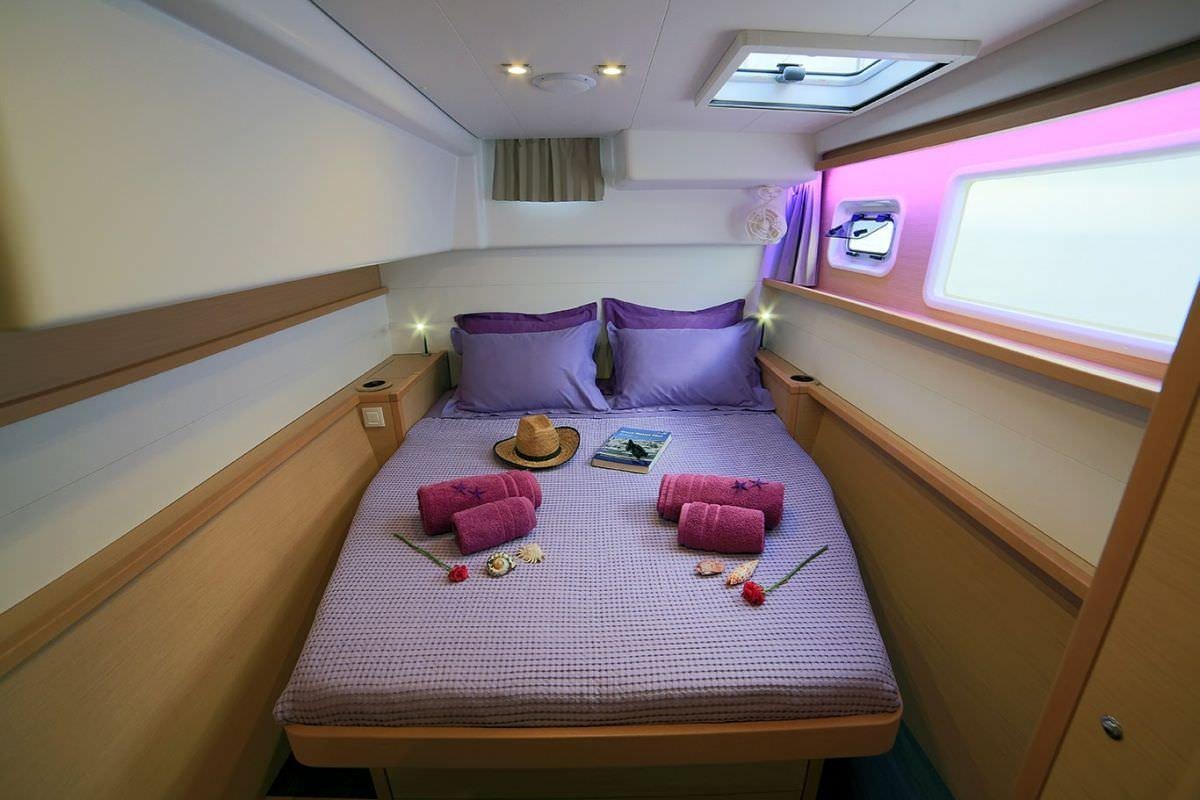 a bed with purple pillows aboard DANIELA II Yacht for Charter