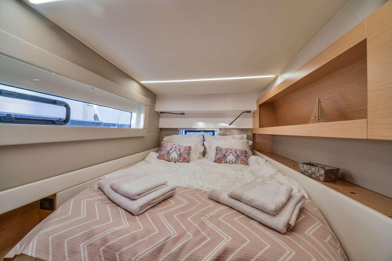 a bed with a pink and white comforter and a window aboard ODYSSEY Yacht for Charter
