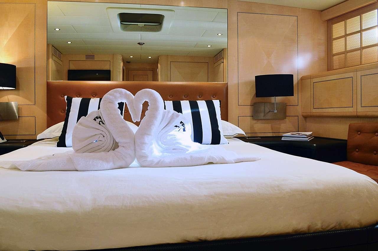 a bed with white sheets and pillows aboard MAMBA Yacht for Charter