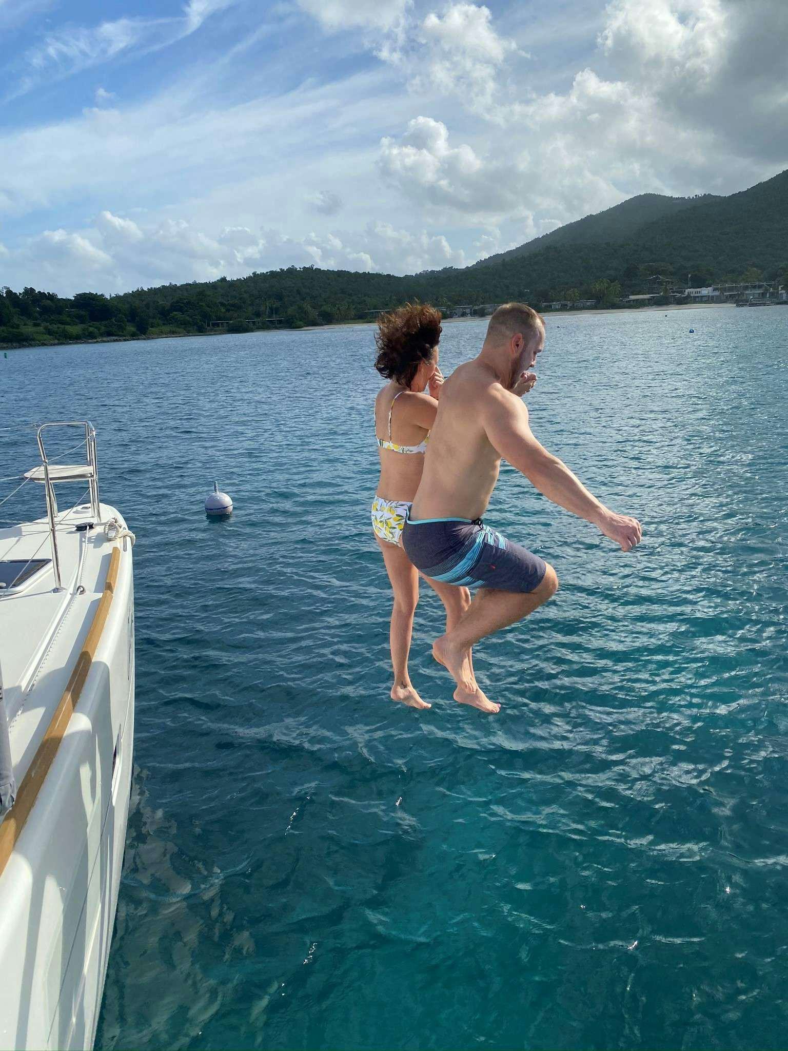 a man and woman jumping into a body of water aboard CHAOS INTERRUPTED Yacht for Charter