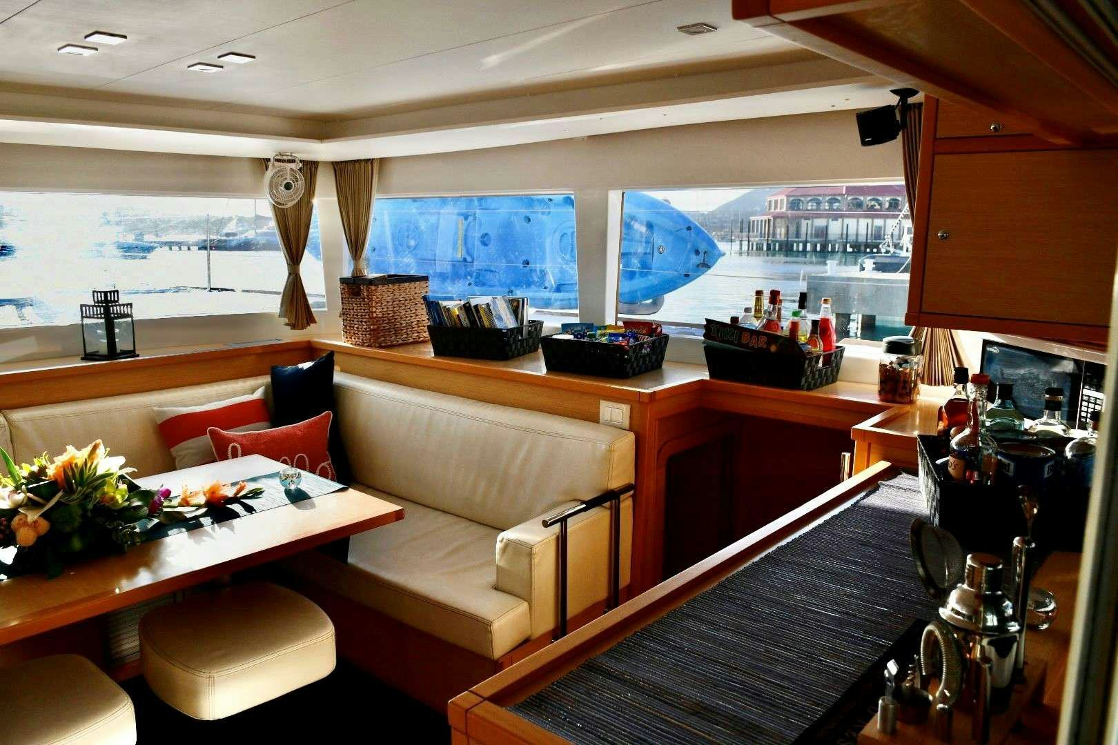 a room with a couch and a table with chairs and a television aboard CHAOS INTERRUPTED Yacht for Charter