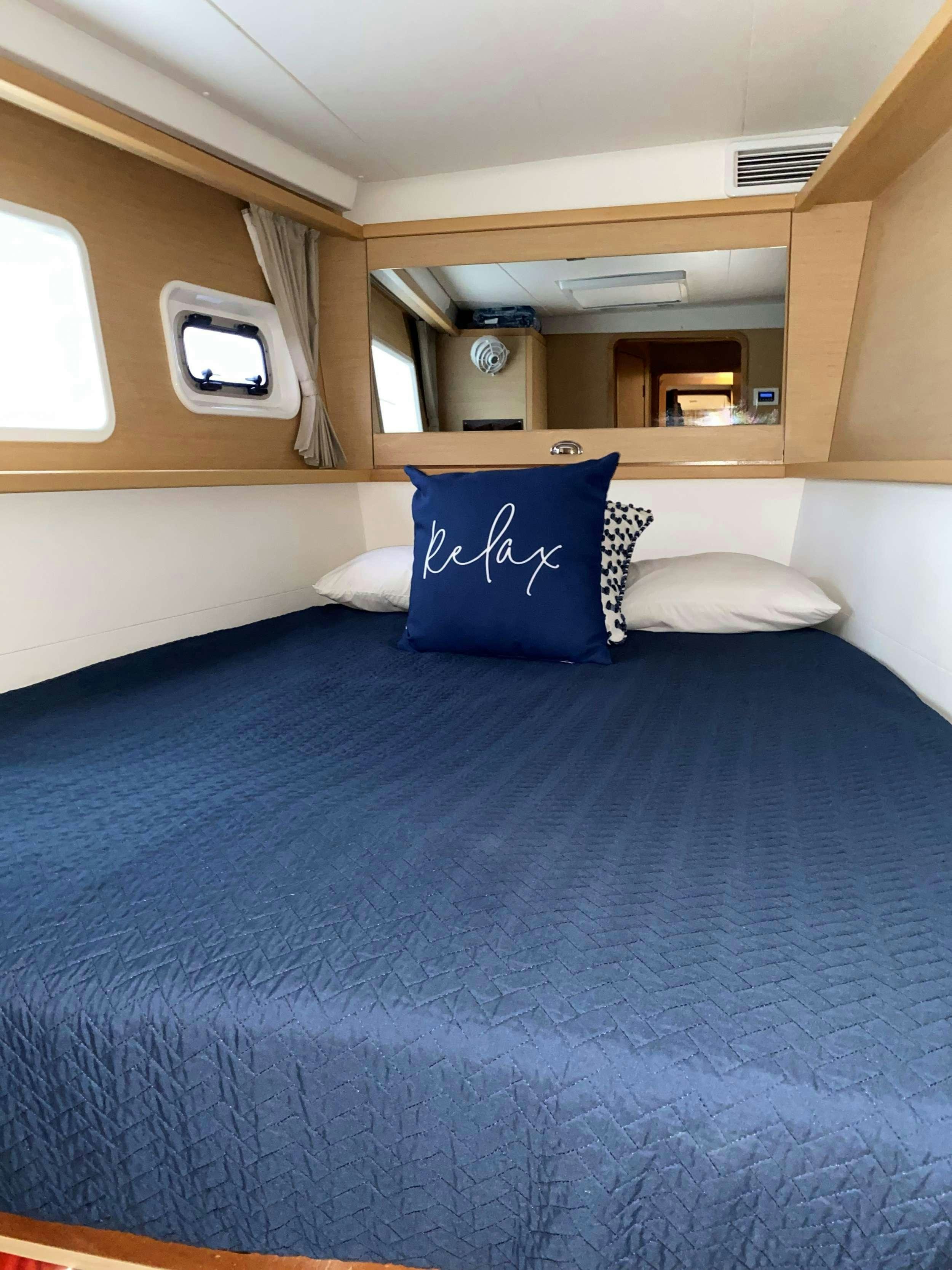 a bed with blue sheets aboard CHAOS INTERRUPTED Yacht for Charter