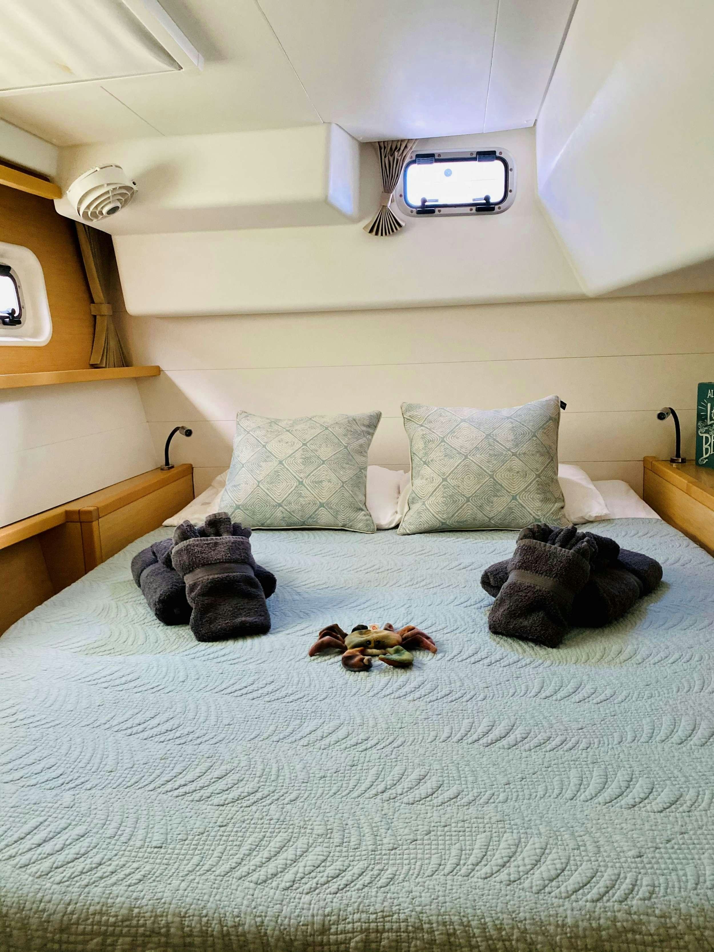 a bed with pillows and a stuffed animal on it aboard CHAOS INTERRUPTED Yacht for Charter