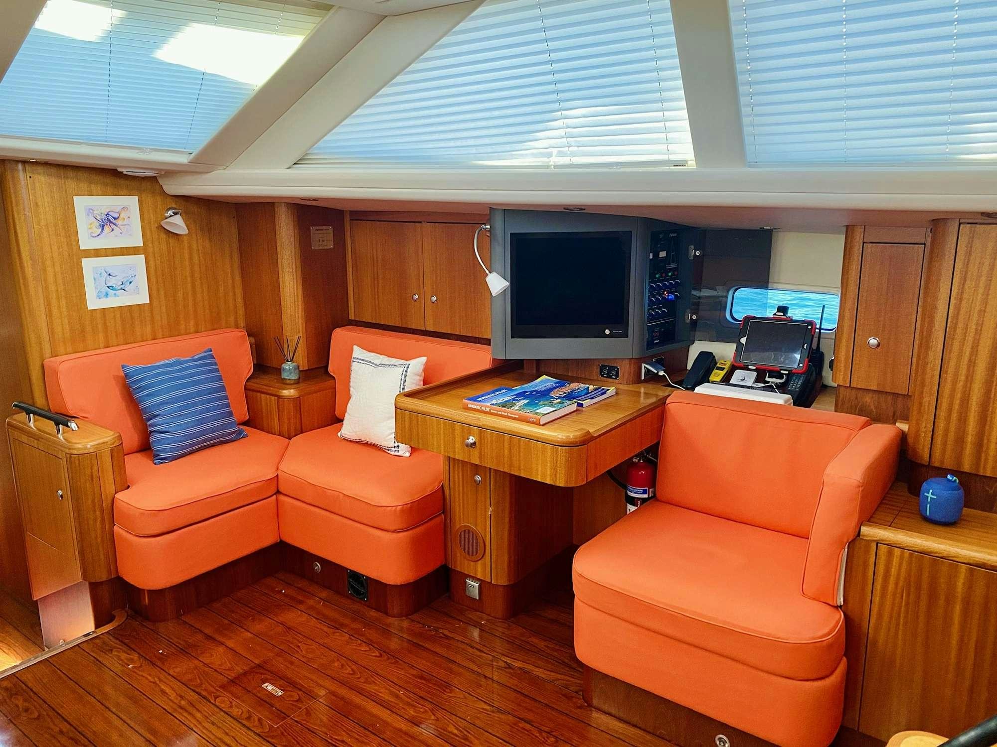 an orange living room with orange couches and a television aboard LUNULATA  Yacht for Charter