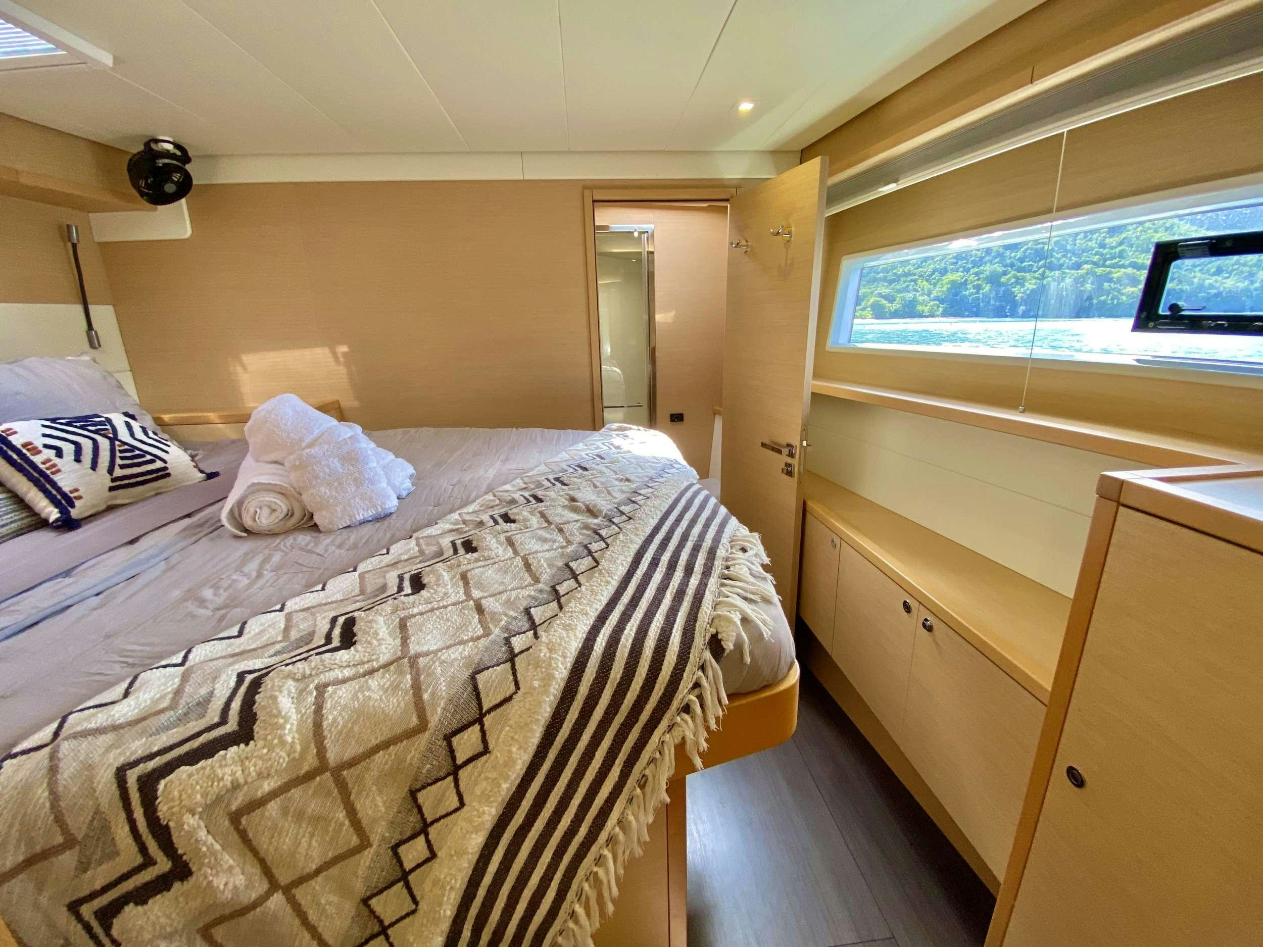 a bedroom with a bed and a window aboard CHAMPAGNE L52 Yacht for Charter