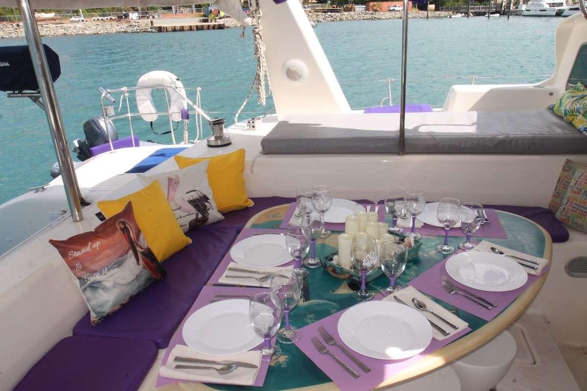 a table with plates and glasses on it by a boat aboard PURPLE PELICAN Yacht for Charter