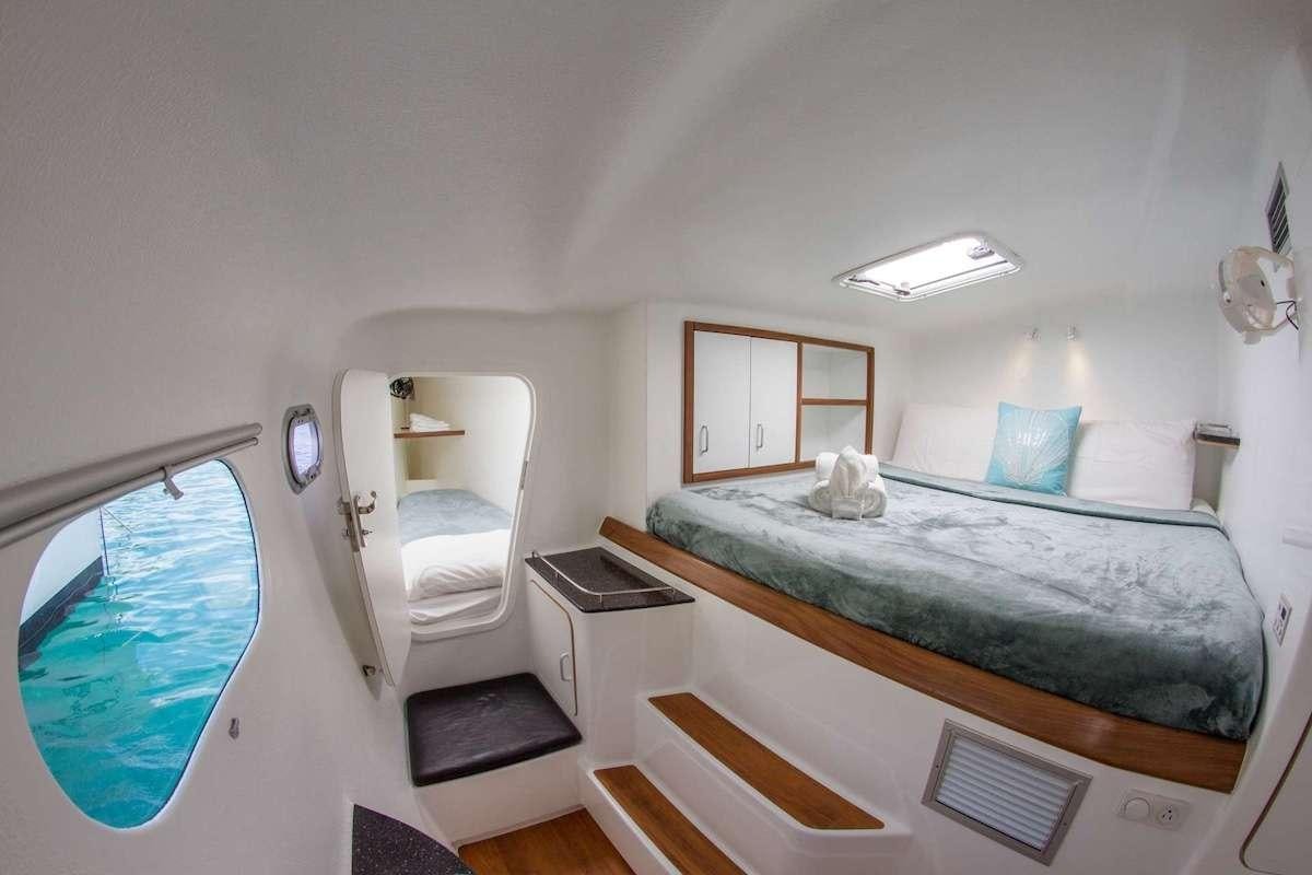 a bedroom with a bed and a window aboard PURPLE PELICAN Yacht for Charter