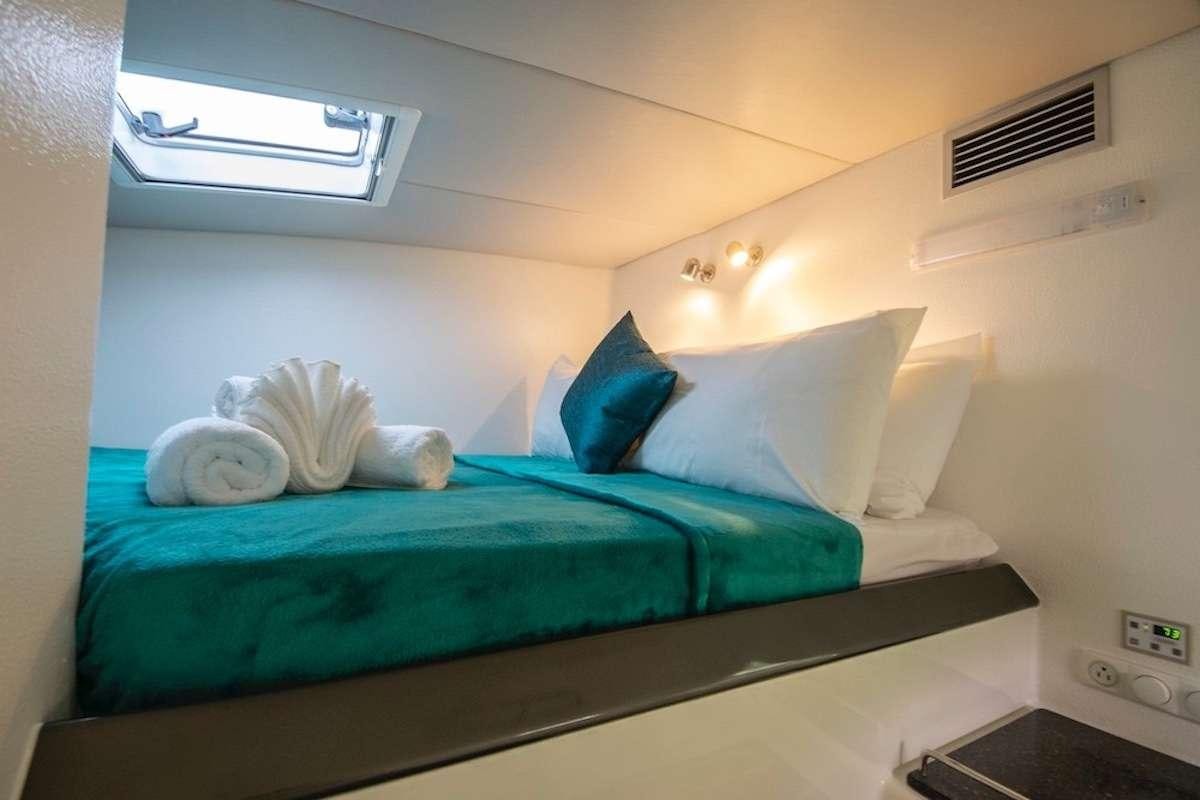 a bed with blue sheets aboard PURPLE PELICAN Yacht for Charter