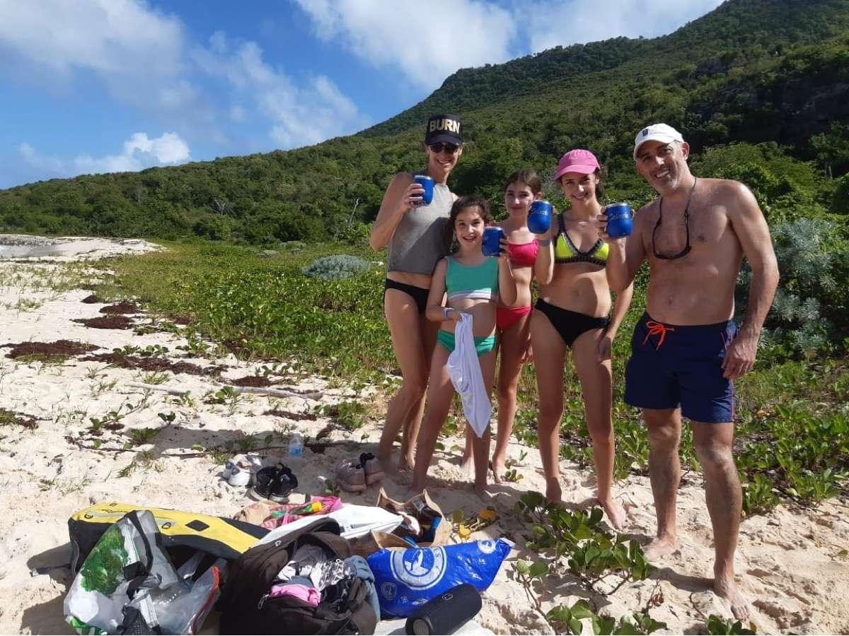a group of people posing for a photo on a beach aboard CELAVIE Yacht for Charter