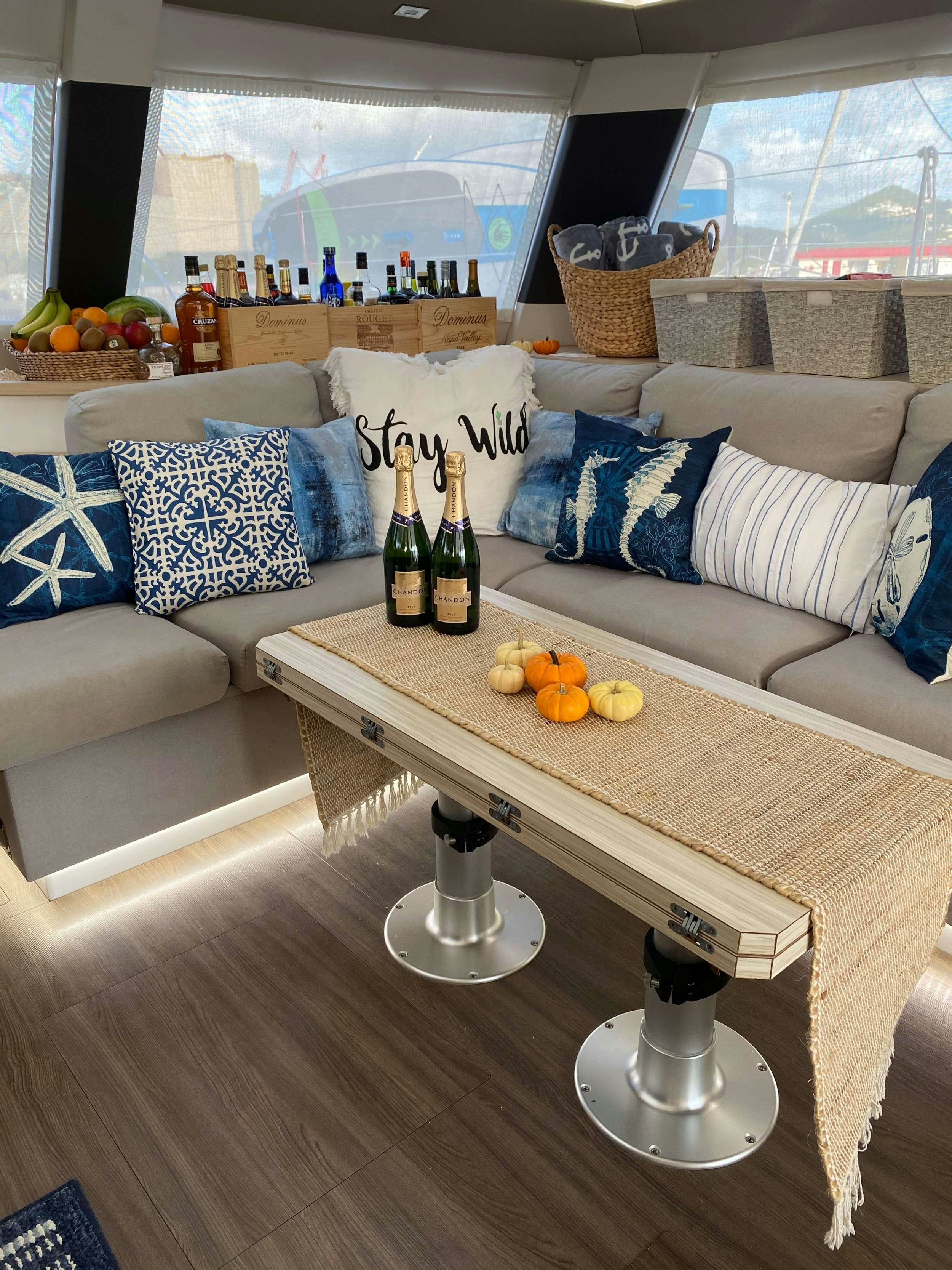 a table with a glass bottle and a couch in the background aboard Sol Mates Yacht for Charter
