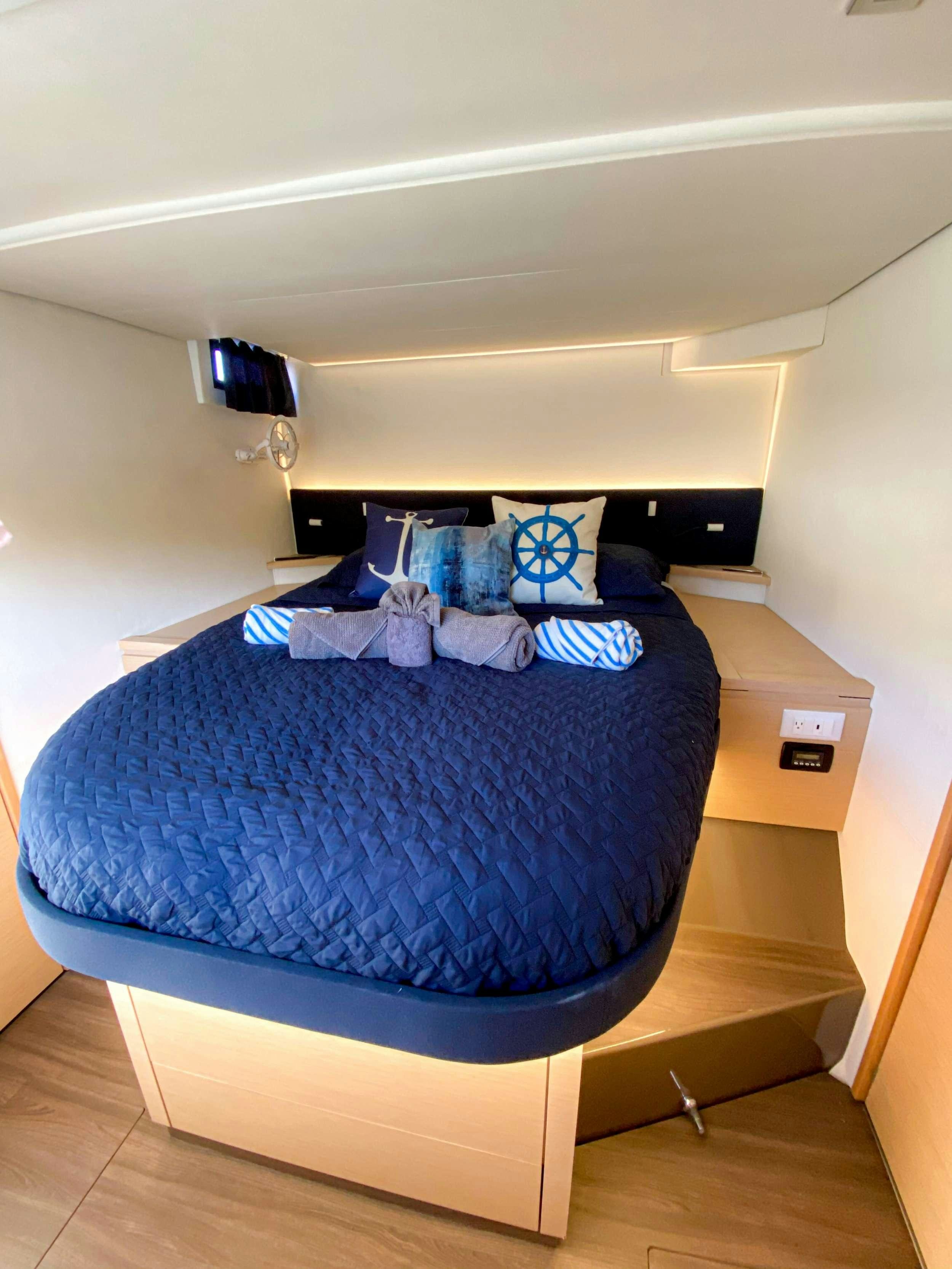 a bed with blue sheets aboard Sol Mates Yacht for Charter