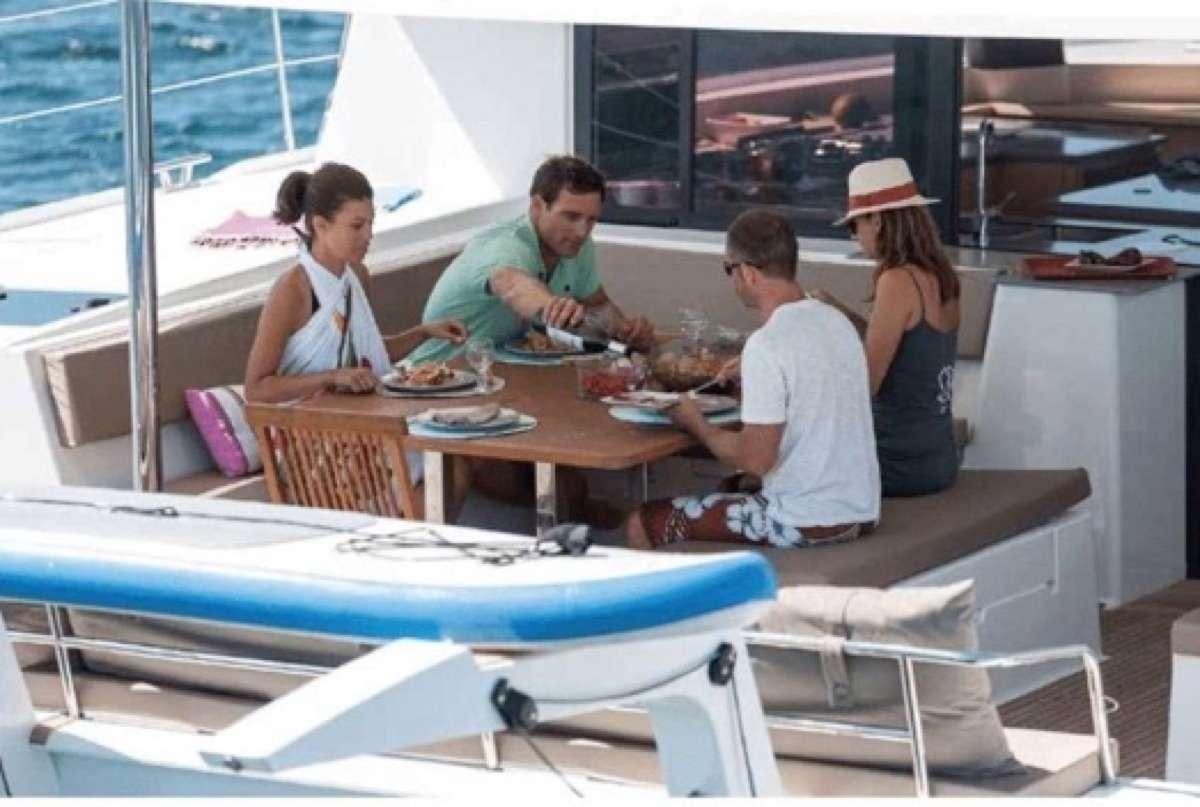 a group of people sitting around a table with food on it aboard Sol Mates Yacht for Charter