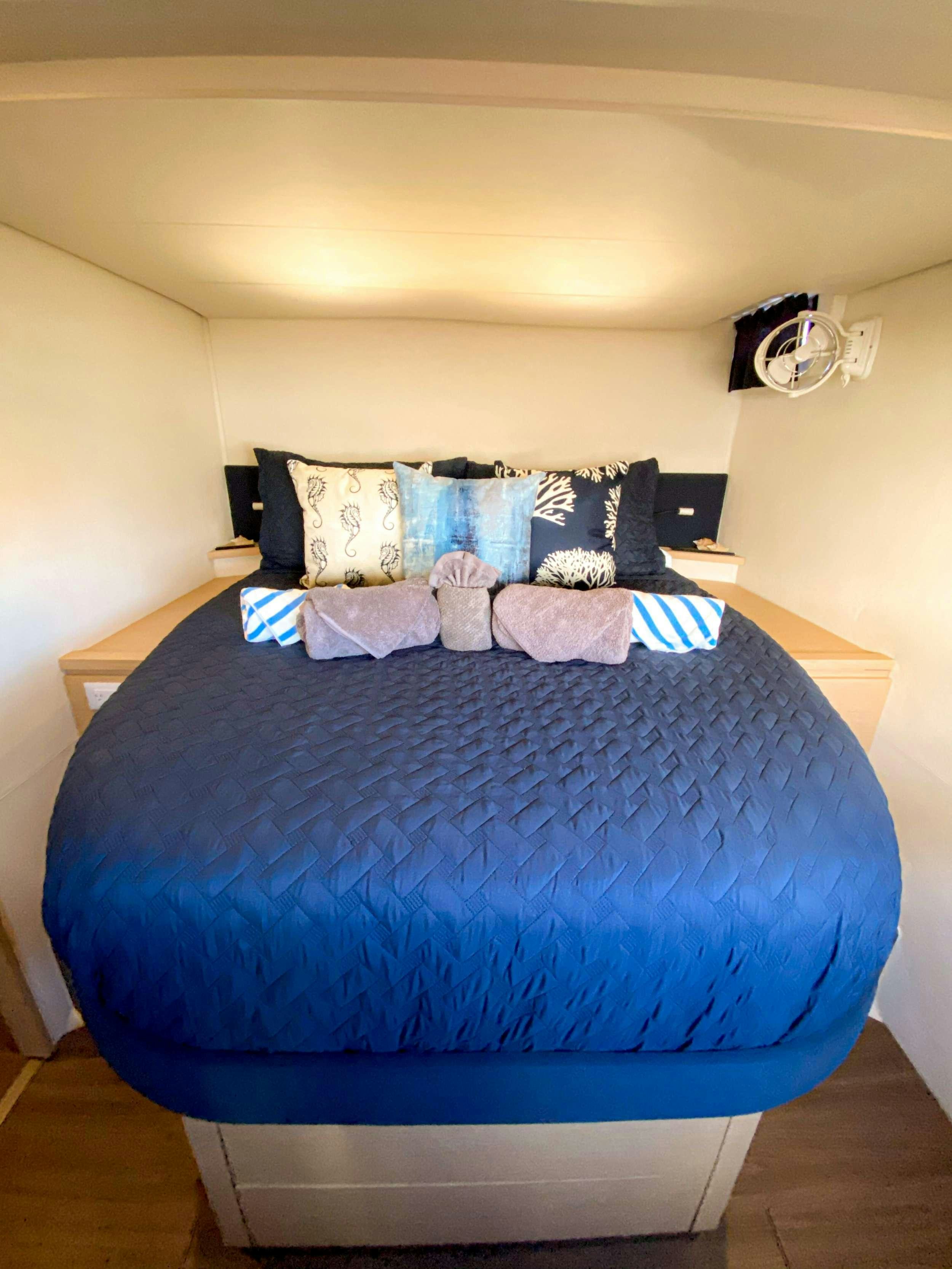 a bed with blue and white sheets aboard Sol Mates Yacht for Charter