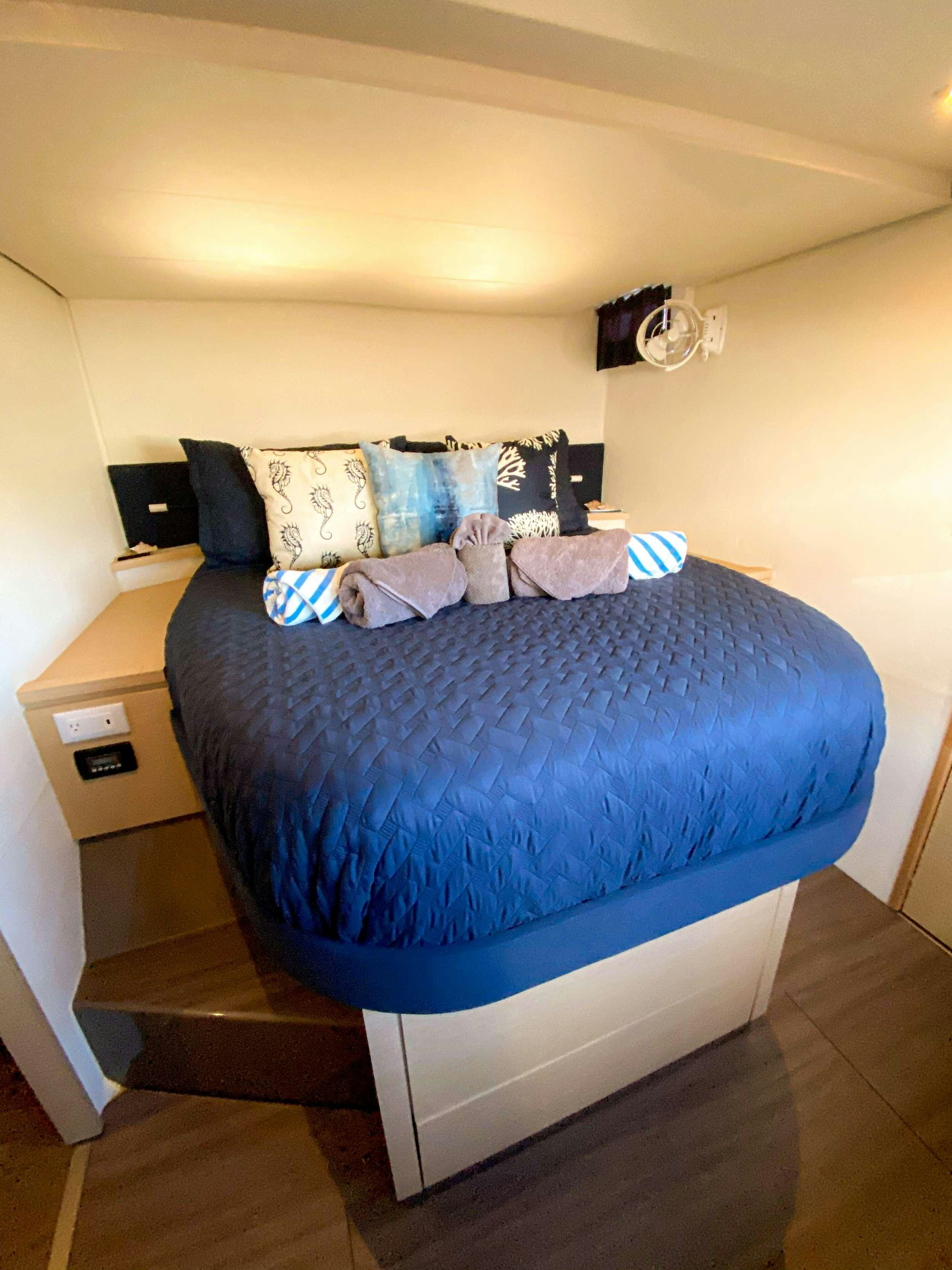 a bed with a blue comforter aboard Sol Mates Yacht for Charter