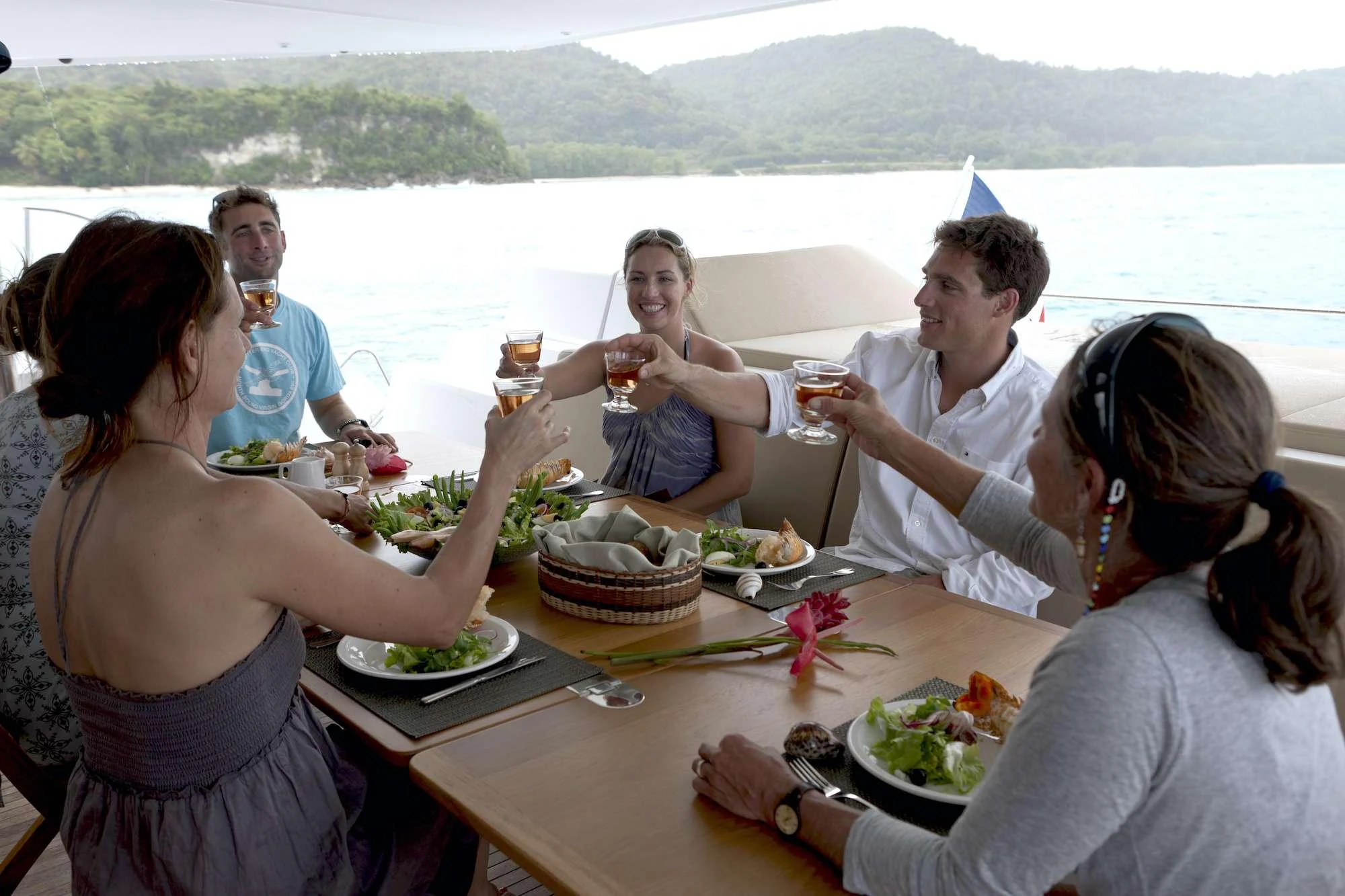 a group of people sitting around a table with food and drinks aboard GRATITUDE Yacht for Charter