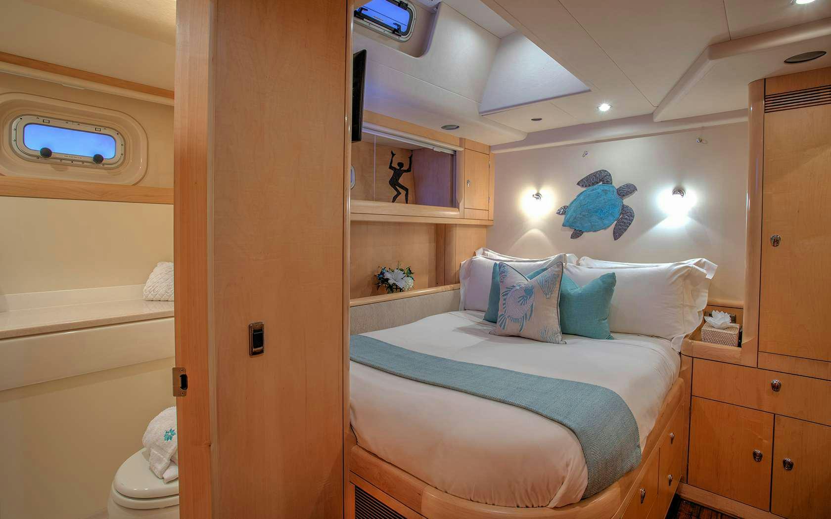 a room with a bed and a shelf with a blue flower on it aboard DAMA DE NOCHE Yacht for Charter