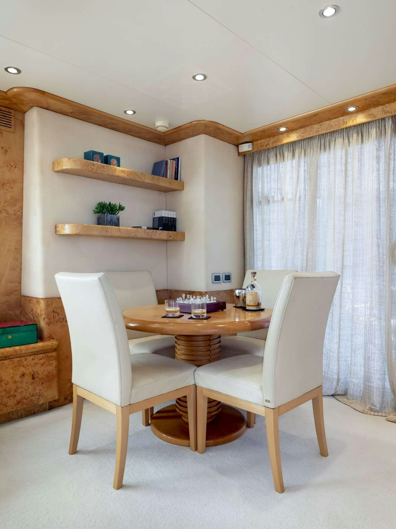 a wooden table and chairs in a room with a wood shelf and a white chair and a wood aboard ANDILIS Yacht for Charter