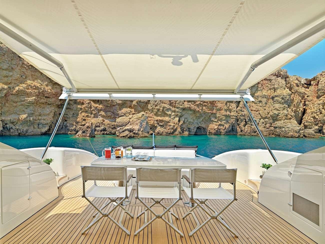 a table and chairs on a balcony overlooking a body of water aboard RUBY Yacht for Charter