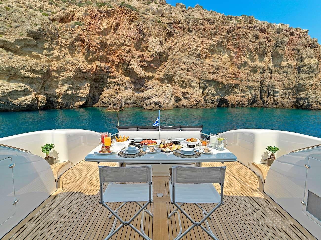 a table set for a meal on a balcony overlooking a body of water aboard RUBY Yacht for Charter