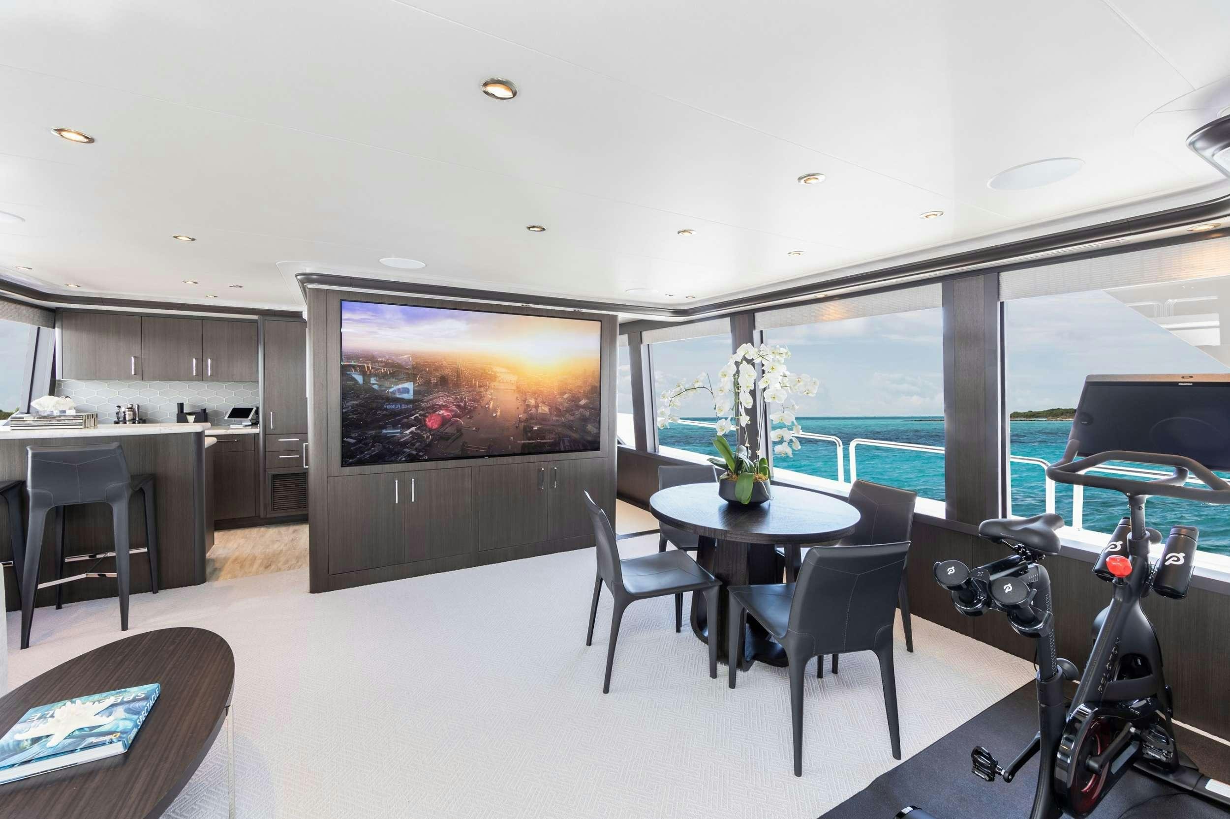 a room with a large screen and a table and chairs aboard NO BAD IDEAS Yacht for Charter