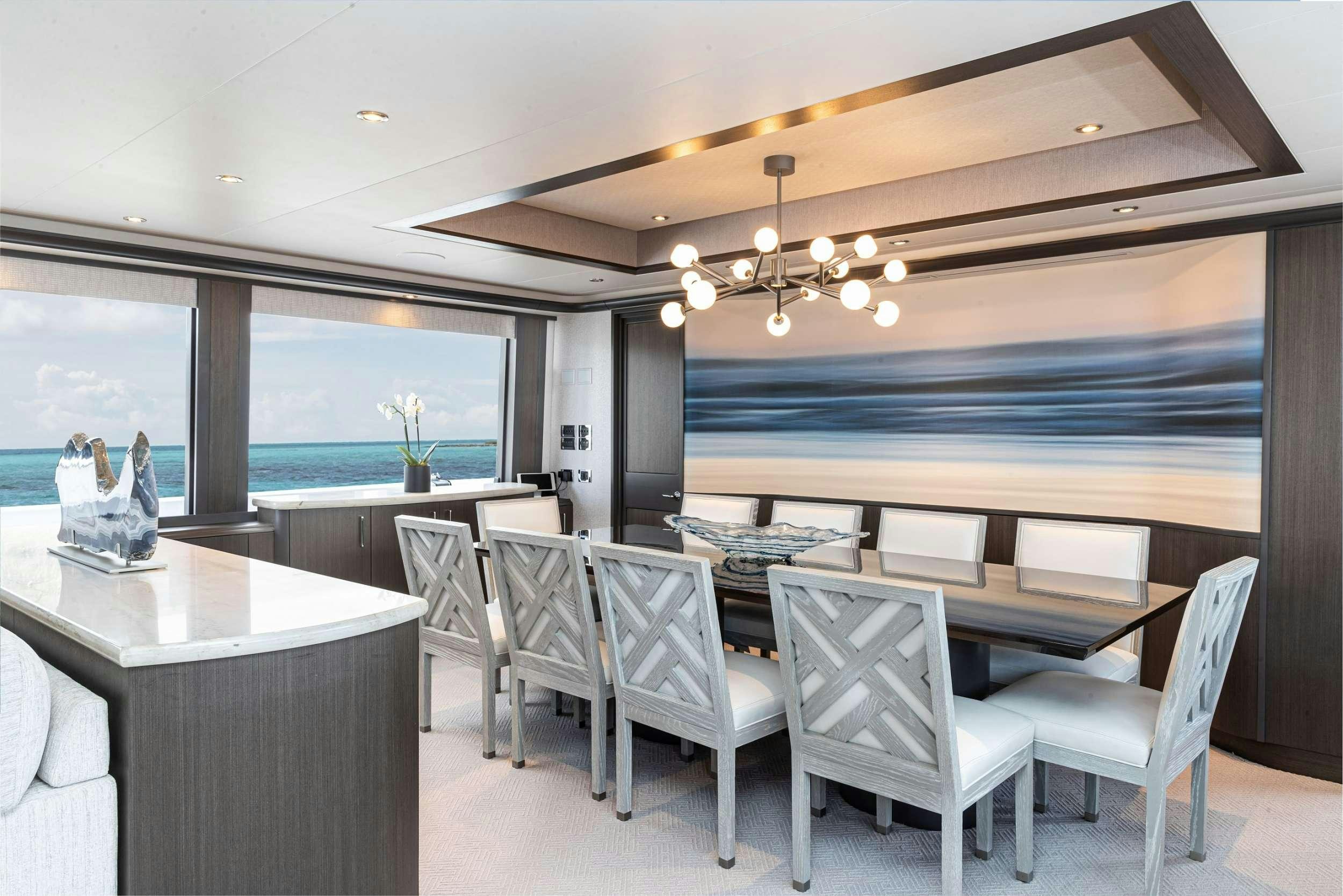 a room with a table chairs and a large window aboard NO BAD IDEAS Yacht for Charter
